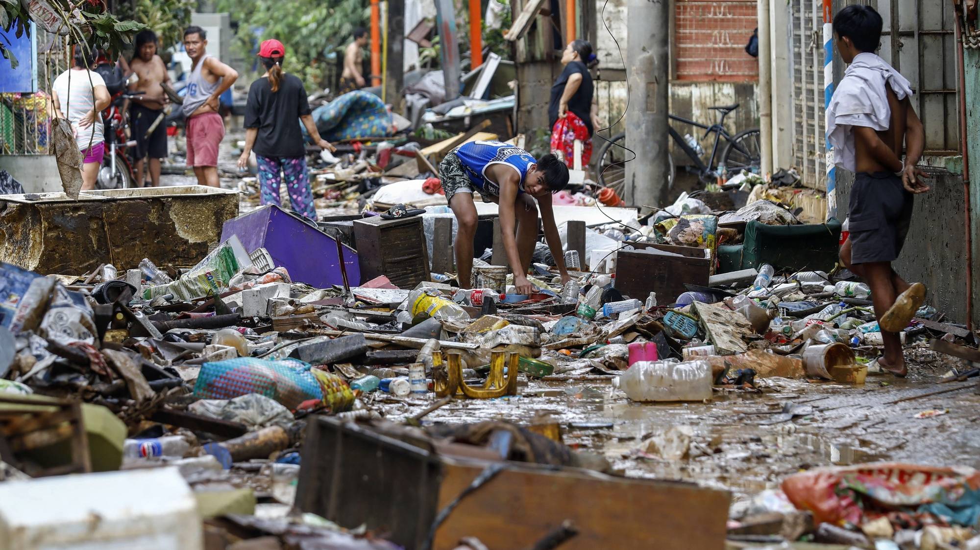 epa11495309 A resident looks for reusable material from trash and debris along a street a day after massive flooding in Marikina City, Metro Manila, Philippines, 25 July 2024. A state of calamity was declared in the Philippine capital of Metro Manila and neighboring provinces in order to activate resources to address effects of massive floods from monsoon rainfall caused by typhoon Gaemi on 24 July. Flood evacuees began returning to their homes while other affected families still remain in evacuation centers in need of relief supplies.  EPA/ROLEX DELA PENA