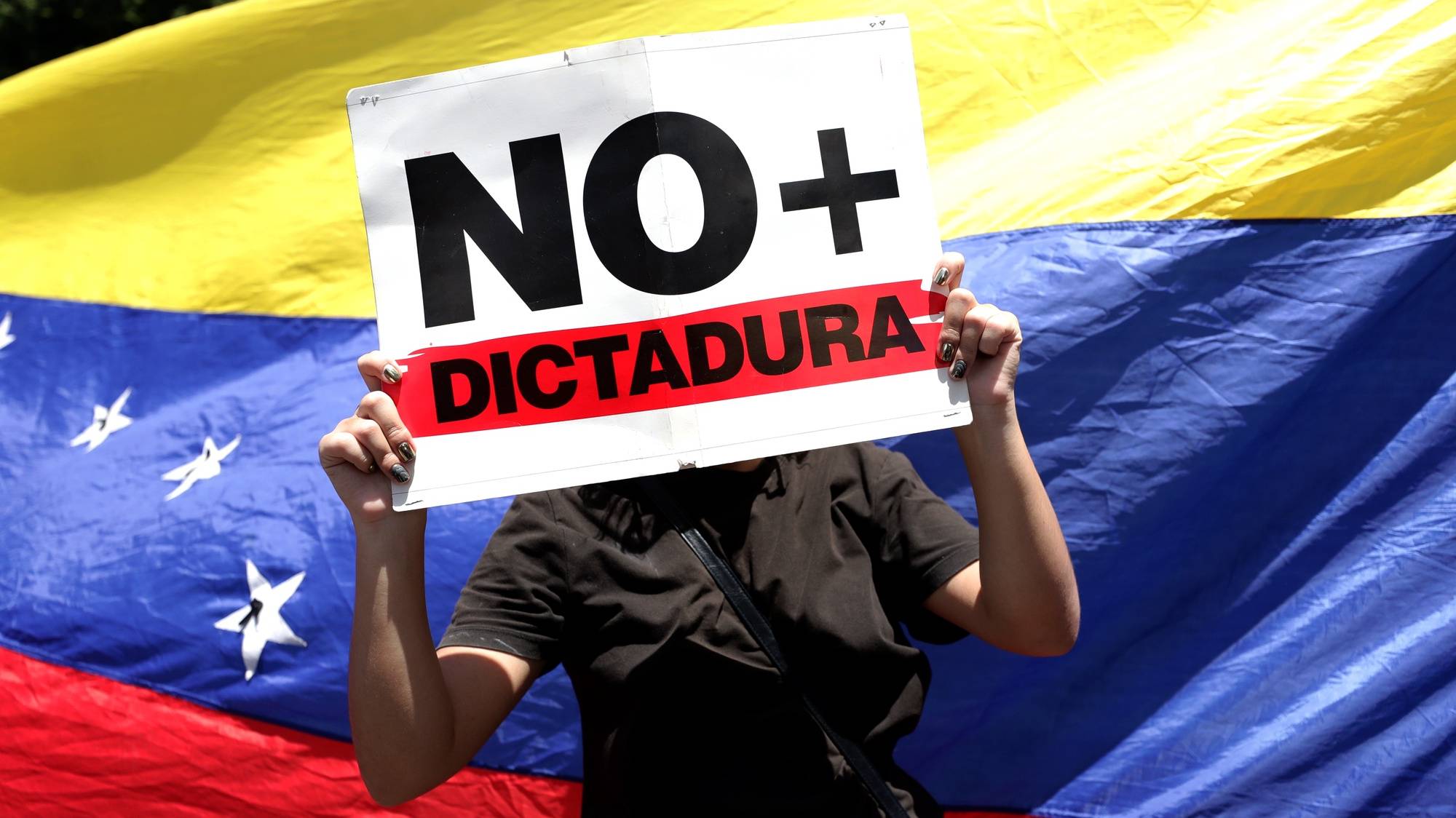 epa11523436 A demonstrator holds a signs reading &#039;No dictatorship&#039; during a protest against the official results of the 28 July presidential elections in Caracas, Venezuela, 03 August 2024. The Venezuelan National Electoral Council (CNE) on 02 August 2024 proclaimed Nicolas Maduro as re-elected president of Venezuela.  EPA/RONALD PENA R.