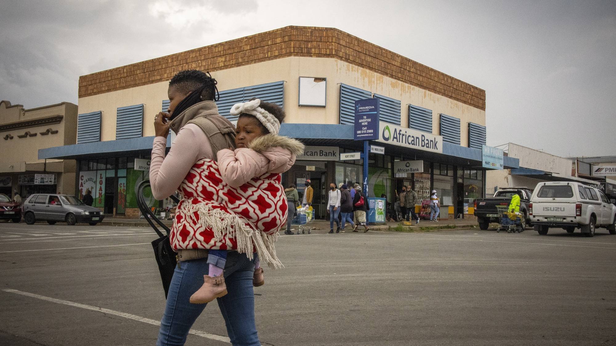 epa09604355 A masked woman carrying a child walks through the streets of the rural town of Parys, South Africa, 26 November 2021. The South African Department of Health and scientists from the Network for Genomic Surveillance revealed details of a newly detected and highly mutated Covid-19 variant, B.1.1.529 which immediately led to Japan, Israel and the European Union placing stricter measures against South Africans travelling to and from their part of the world.  EPA/KIM LUDBROOK