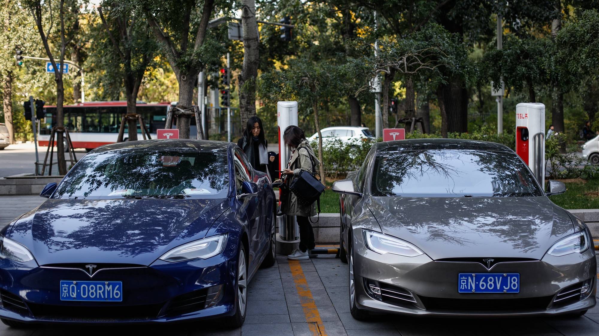 epa06283672 A woman unplugs her Tesla electric car from a charger at a charging station in Beijing, China, 23 October 2017. China plans to ban fossil fuel-powered cars in the future while promoting hybrids and electric vehicles - a goal the country shares with other countries, such as France and the UK, which also have plans to ban the sale of cars powered by fossil fuels by 2040.  EPA/ROMAN PILIPEY