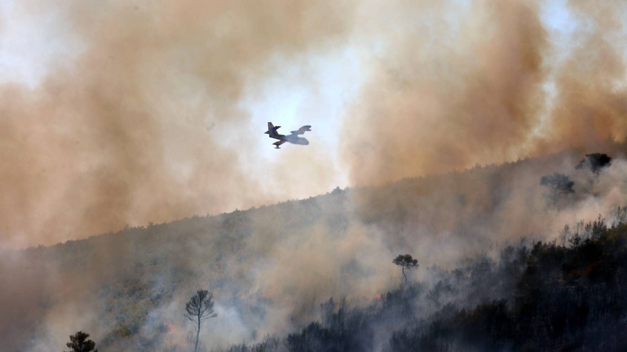 epa11546405 Α firefighting airplane drops water during a  wildfire in Grammatiko, northeast Attica, Greece, 12 August 2024. The wildfire that broke out in Varnavas on 11 August afternoon continues to rage in Eastern Attica on 12 August, fanned and spread to a front extending more than 20 kilometers. According to the fire department, the fire-fighting effort is extremely difficult as the wind keeps changing direction, while the three main fronts of concern are in Grammatiko, Penteli and the Anatoli settlement in Nea Makri.  EPA/ALEXANDROS BELTES