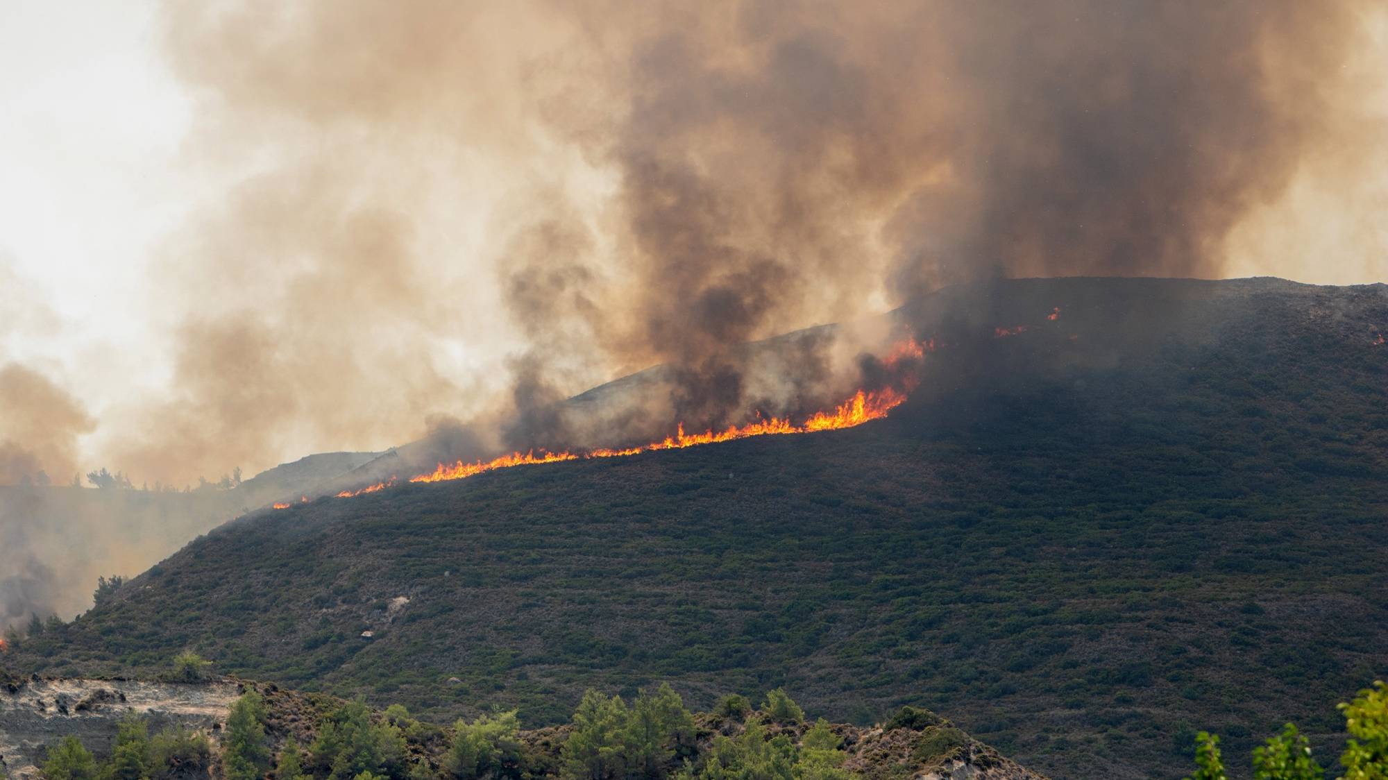 epa10769916 A wildfire burns in Vati village, on Rhodes island, Greece, 26 July 2023. The Fire Brigade forces are battling the rekindled fire fronts in the region of southern Rhodes assisted by hundreds of volunteers and firefighting aircraft constantly dropping water from above. The continuing fight to put out rekindled fire fronts in southern Rhodes continued as a state of emergency now including the entire island allowing the region to draw emergency funding to restore damaged property.  EPA/DAMIANIDIS LEFTERIS