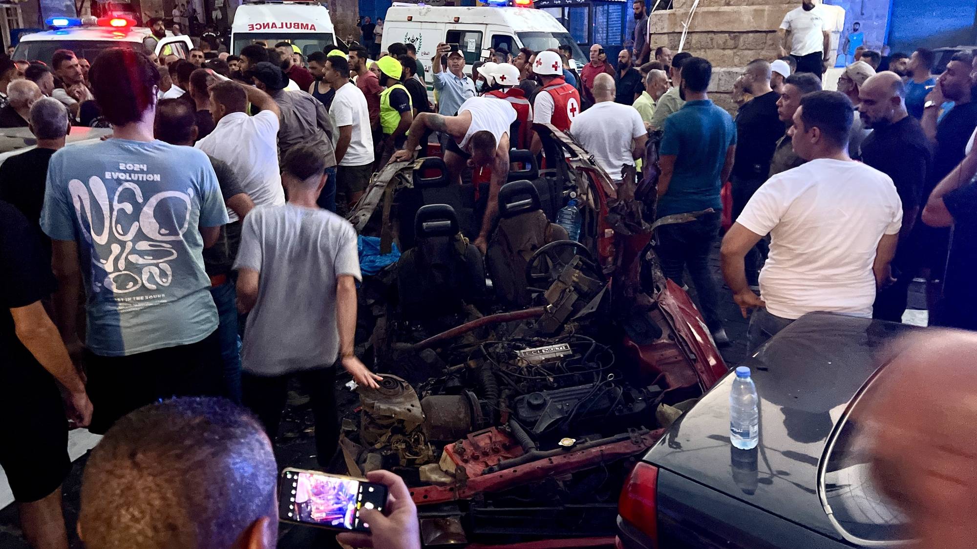 epaselect epa11549081 People stand around the wreckage of a car following a drone attack, in Marjayoun, southern Lebanon, 14 August 2024. According to the Lebanese Ministry of Health, at least two people were killed, and four others were injured in an Israeli drone attack targeting a car in Marjayoun. There was no immediate comment from Israel on the incident.  EPA/STRINGER