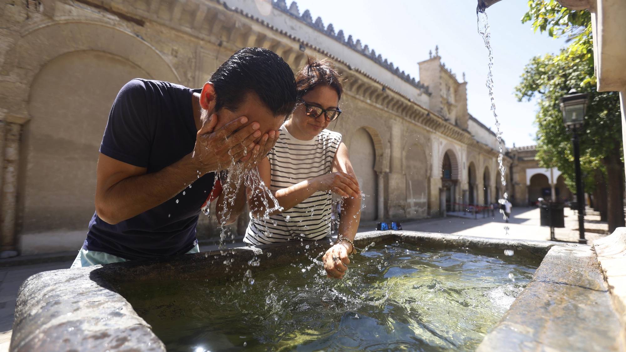 epa11530754 Two tourists refresh themselves in a fountain in Cordoba, southern Spain, 06 August 2023. Spain is fully immersed in the characteristic &#039;canicula&#039; or dog days period, between July 15 and August 15, with temperatures hovering around 40 degrees in many places and dry and sunny weather in practically the entire country.The &#039;canicula&#039; is a very hot period of the year, with temperatures hovering in Spain around 40 degrees in many places.  EPA/SALAS