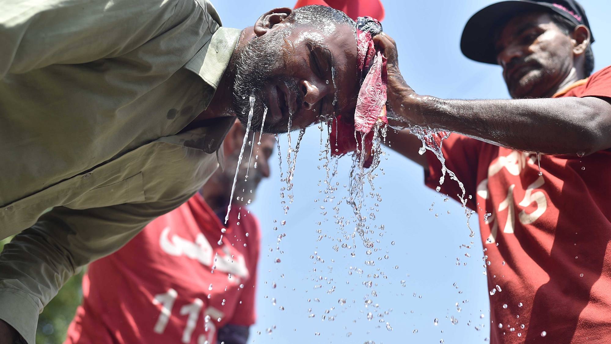 epa11363278 A volunteer pours cold water on people on a roadside on a hot day in Karachi, Pakistan, 22 May 2024. The Pakistan Meteorological Department (PMD) has issued a warning for an ongoing heatwave across most parts of the country. Temperatures are expected to gradually rise, with a possibility of exceeding 50 degrees Celsius in some areas over the next few days.  EPA/SHAHZAIB AKBER