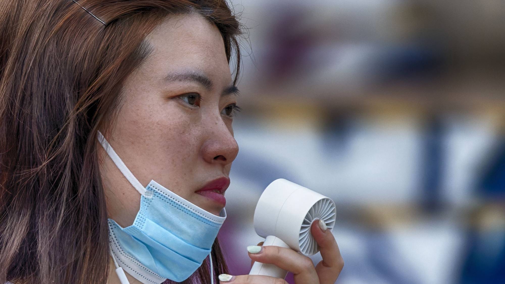 epa10128809 A woman uses a portable fan for cooling as she walks on a street in Shanghai, China, 19 August 2022. China has issued a national drought alert as regions from Sichuan in the southwest to Shanghai in the Yangtze delta have been experiencing high temperatures with the district of Beibei in Chongqing reaching up to 45 degrees Celsius.  EPA/ALEX PLAVEVSKI