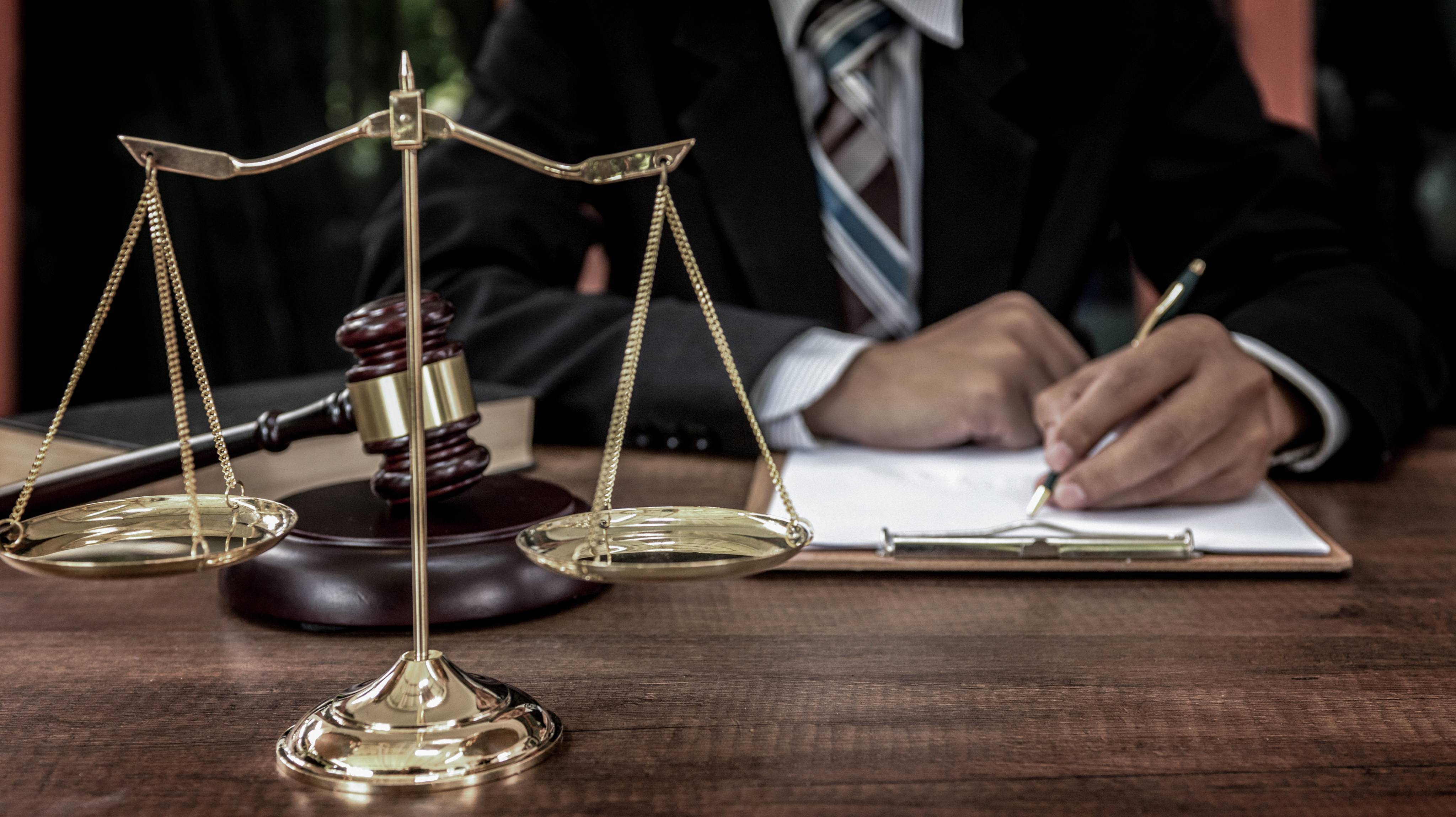 Tribunal attorney lawyer working with documents and wooden judge gavel on table in courtroom.