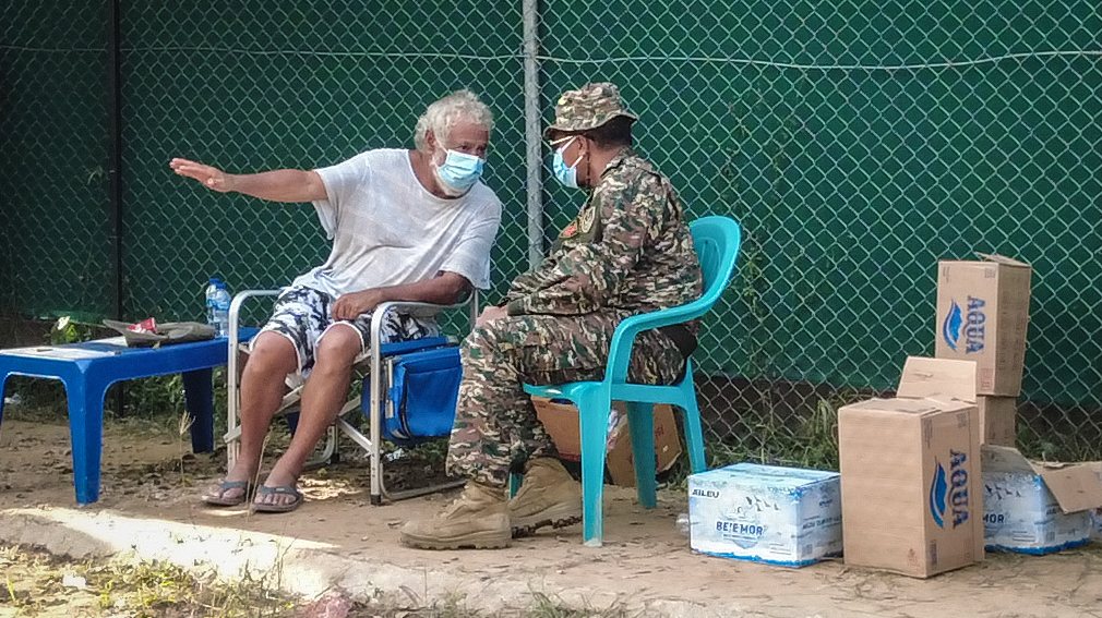 Timorese historical leader Xanana Gusmao (L) remains adamant and is still sitting under a green awning outside the center, located on Rumbia crossing, refusing to leave the site, in solidarity with the family of the deceased, in Dili, East Timor, 12 April 2021. ANTONIO SAMPAIO/LUSA