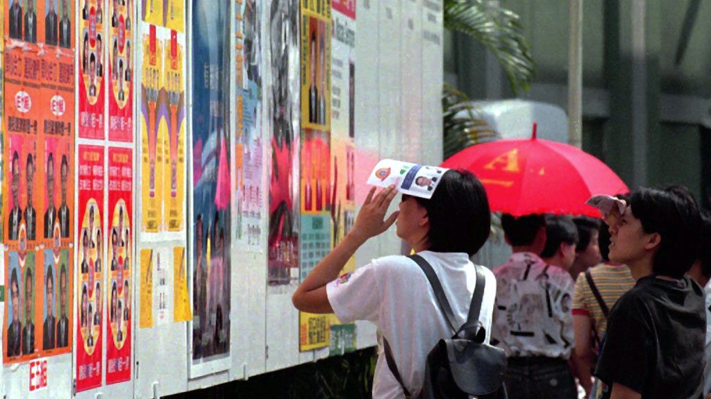 Habitantes observam cartazes de propaganda eleitoral antes da votação para a Assembleia Legislativa do territorio