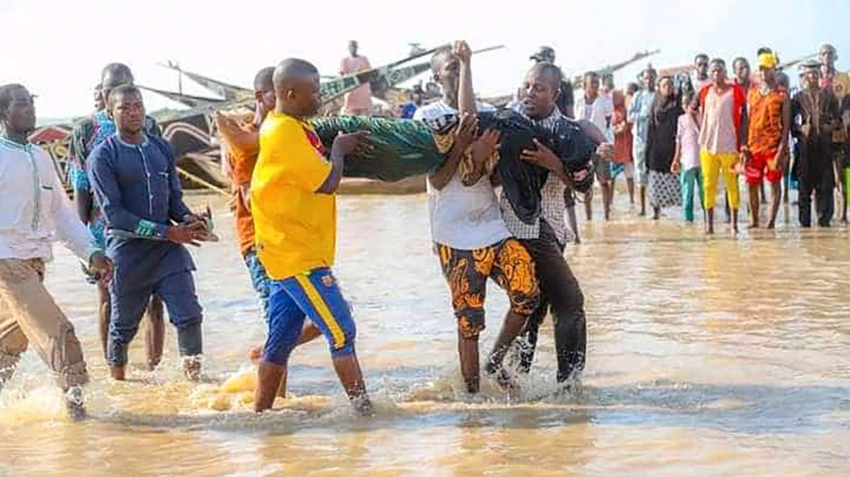 epa09231147 Nigerians carry the body of a drowned victim following a boat accident in Kebbi, Nigeria 26 May 2021 (issued 27 May 2021). According to Nigeria government authorities more than 100 are missing following a boat accident in the northwestern Nigerian state of Kebbi. The vessel had around 180 onboard when it split in half and sank.  EPA/STR BEST QUALITY AVAILABLE