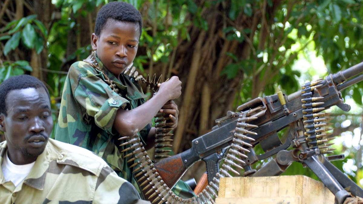 A Chadian child soldier (R) stands in front of a machine gun 24 March 2003 at De Roux camp in Bangui, Central Africa, where stolen objects and arms are stored since the 15 March coup against Ange-Felix Patasse.
AFP PHOTO  DESIREY MINKOH