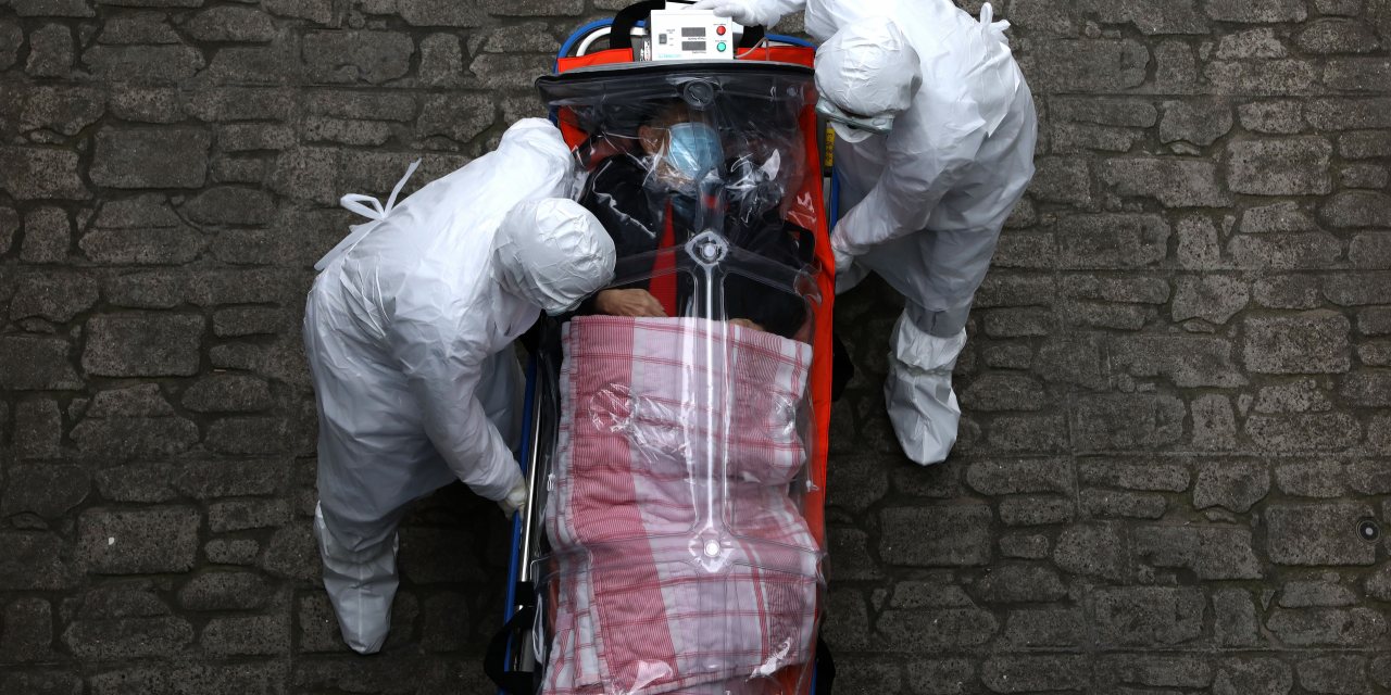 Doente infetado com Covid-19 é transportado por pessoal médico de uma ambulância para dentro do hospital, em Seul