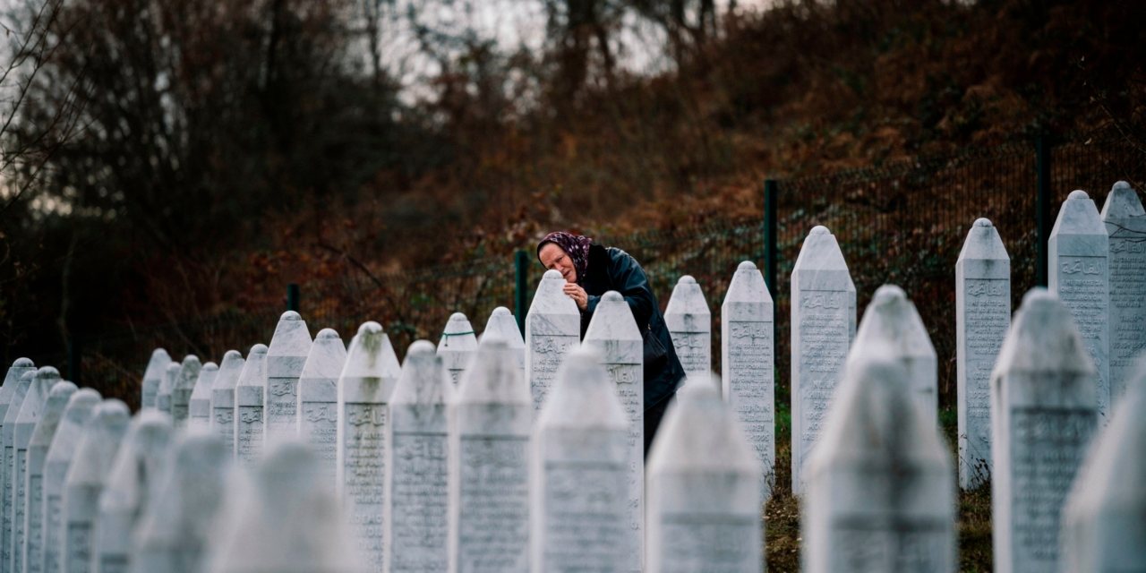 Mulher chora junto às lápides de um cemitério onde foram enterrados restos mortais de vítimas do massacre de Srebrenica