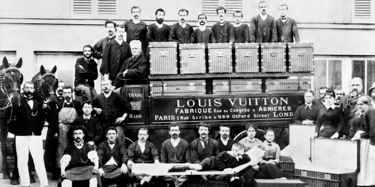 No pátio das oficinas de Asnières Workshops, por volta de 1888. Louis, Georges e Gaston L. Vuitton (sentado numa mala-cama)