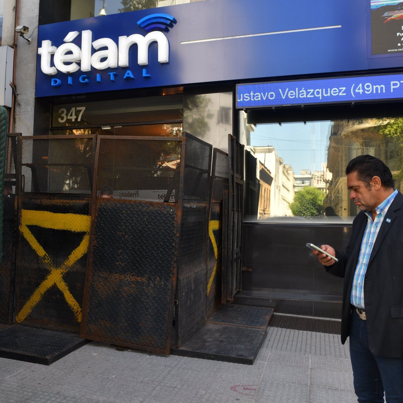 epa11199152 A journalist looks at his cell phone outside the state news agency Telam, whose doors are barricaded, in the San Telmo neighborhood in Buenos Aires, Argentina, 04 March 2024. After the Argentinian President announced the closure of the state news agency Telam, the website appeared as a &quot;page under reconstruction&quot; and the door to the headquarters appeared fenced. The workers gathered in a symbolic &#039;hug&#039; to defend the public media, which, throughout the weekend, received the support of the national and international journalistic world  EPA/ENRIQUE GARCIA MEDINA
