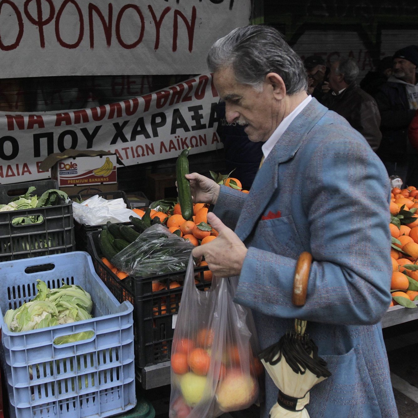 epa05112639 A man takes vegetables as open-air fruit and vegetable vendors block with their products the entrance of Labor Ministry, downtown Athens, Greece, and gave away their produce to passersby, on 20 January 2016. The protesters oppose government&#039;s plans on social insurance and pension reforms.  EPA/ORESTIS PANAGIOTOU