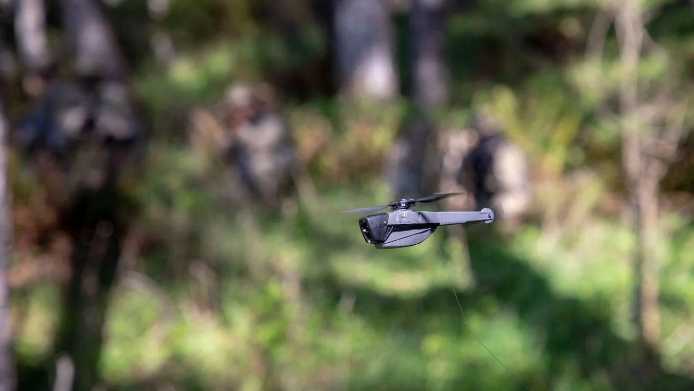 Drone Black Hornet em voo com árvores de fundo