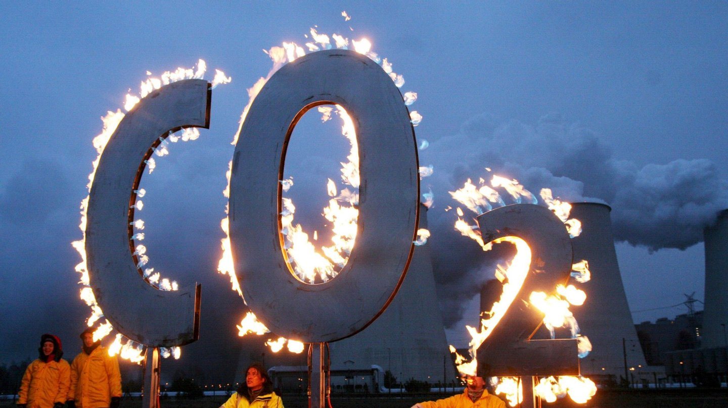 Membros da Greenpeace manifestam-se contra as estações de emissão de carbono ao queimarem as letras &quot;CO2&quot;