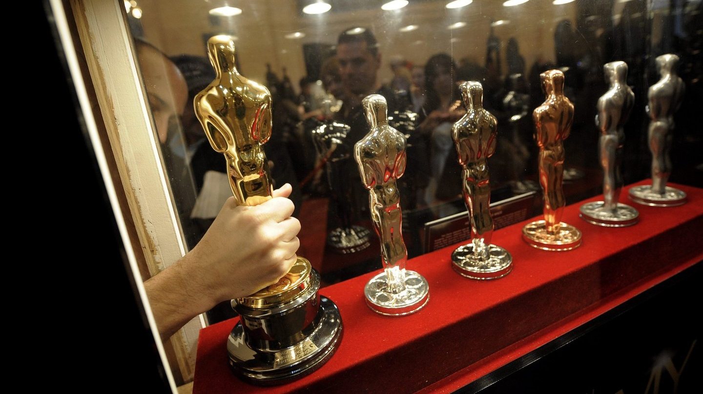 Um membro do staff faz ajustes para colocar uma estátua dos Oscares junto das outras na Academia