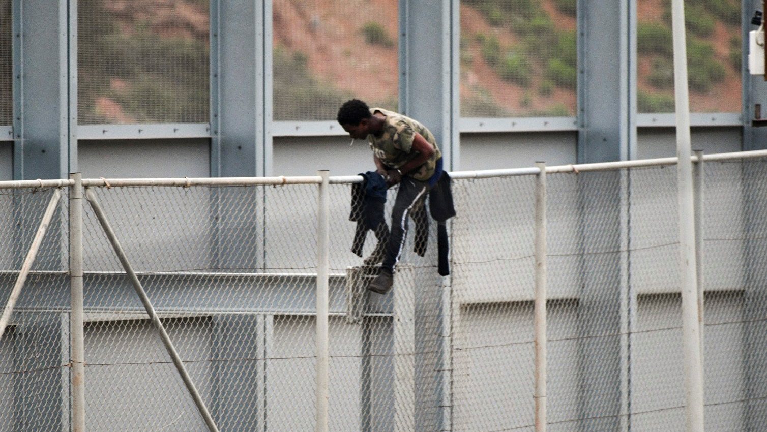 epa09132259 A migrant jumps the fence between Morocco and Ceuta, Spanish enclave on the North of Africa, 13 April 2021.  EPA/Reduan Dris