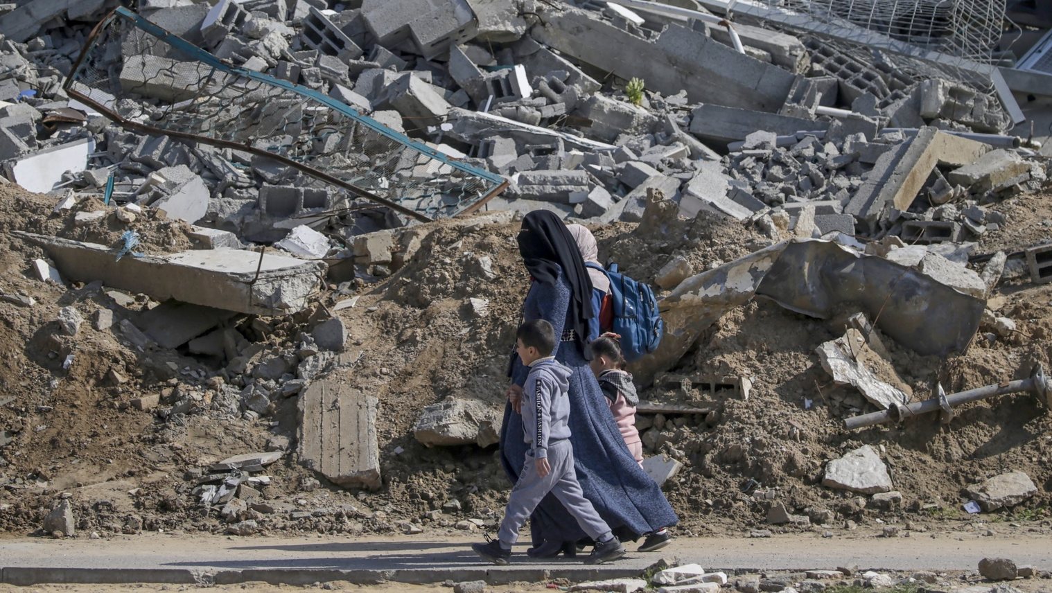 epa11186904 A Palestinian mother walks with her children next to the rubble of a destroyed residential building in Al Nuseirat refugee camp, central Gaza Strip, 28 February 2024, following Israeli air strikes. More than 29,900 Palestinians and over 1,300 Israelis have been killed, according to the Palestinian Health Ministry and the Israel Defense Forces (IDF), since Hamas militants launched an attack against Israel from the Gaza Strip on 07 October 2023, and the Israeli operations in Gaza and the West Bank which followed it.  EPA/MOHAMMED SABER