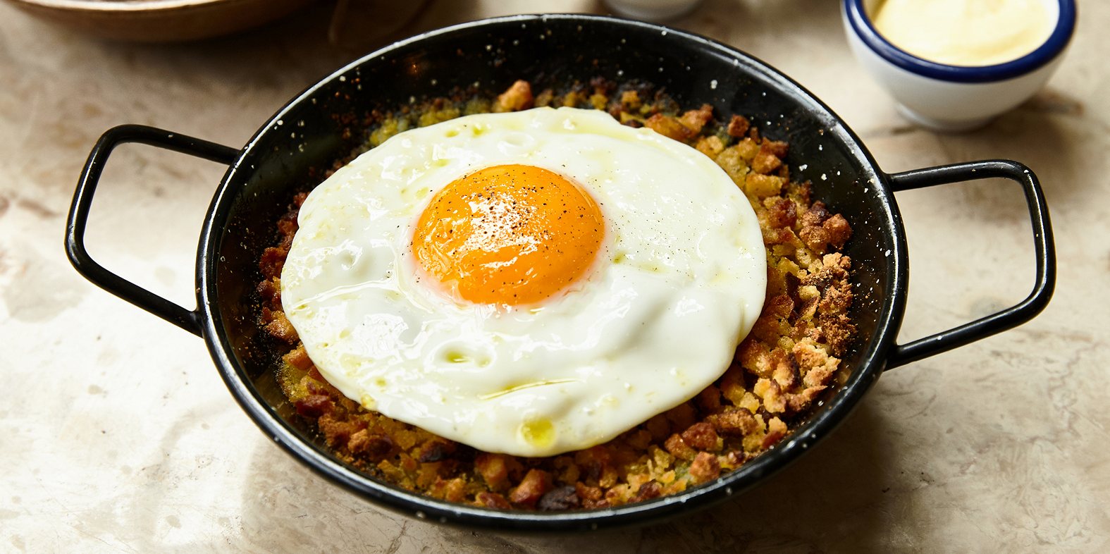 Este bacalhau lascado com ovo estrelado integra o menu de almoço da Taberna do Bairro do Avillez ©DR