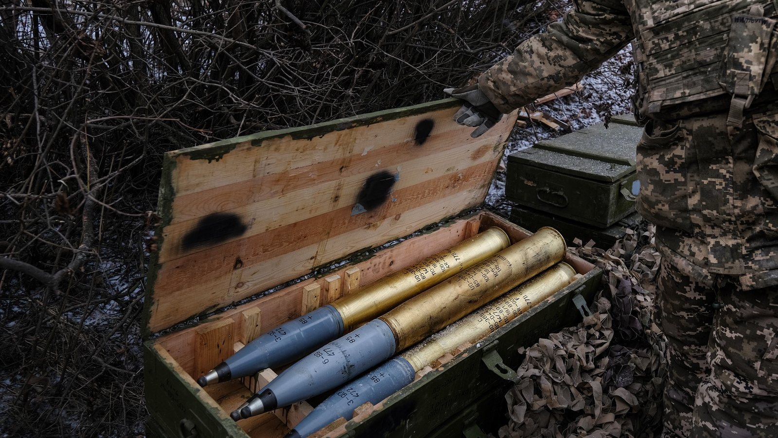 epa11016126 A Ukrainian serviceman of the 22nd Mechanized Brigade shows a crate with artillery shells at their position near the frontline city of Bakhmut, eastern Ukraine, 07 December 2023. Russian troops entered Ukrainian territory in February 2022, starting a conflict that has provoked destruction and a humanitarian crisis.  EPA/MARIA SENOVILLA