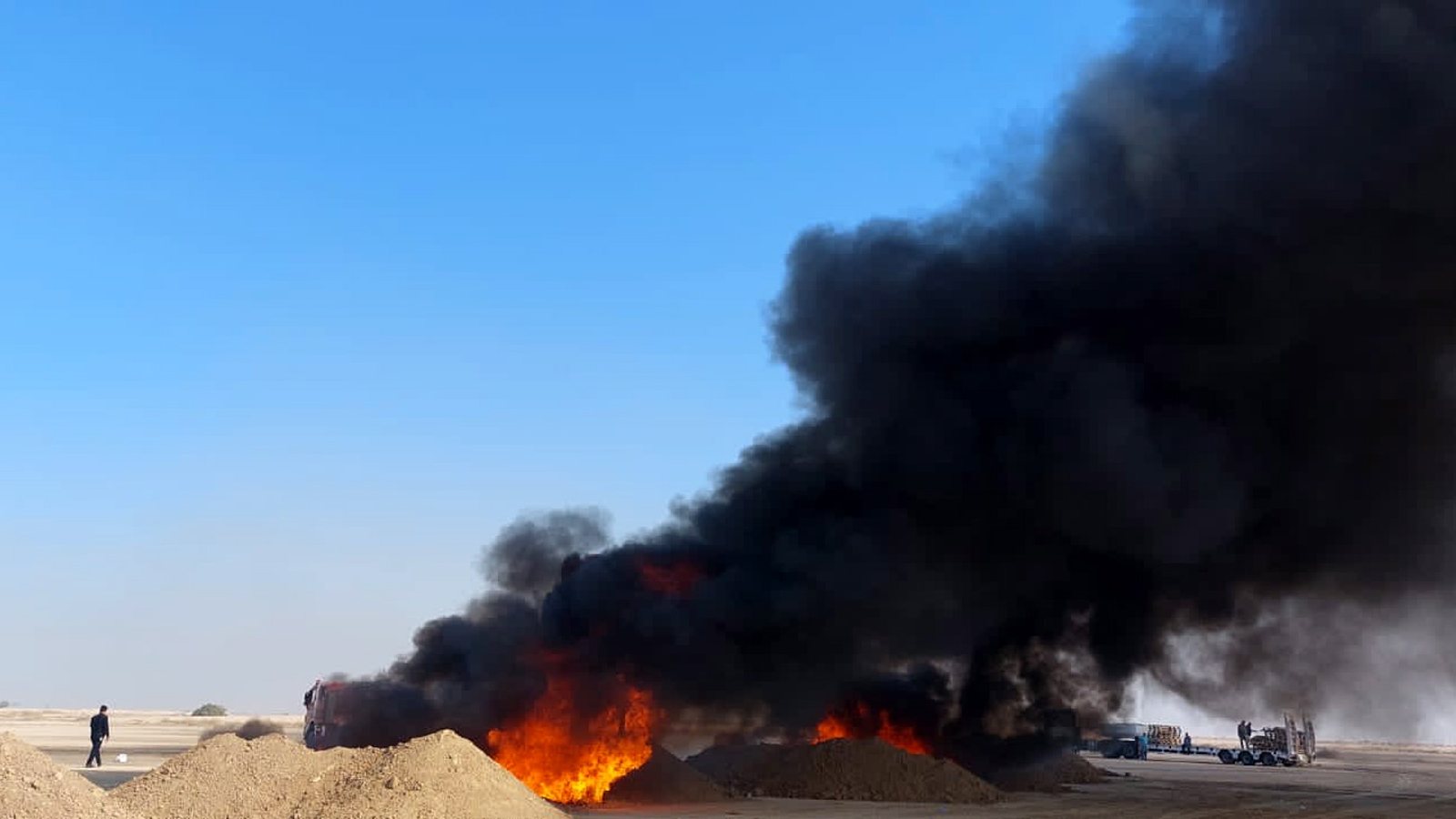 epa10372799 Fire and smoke rising from the place of destruction of confiscated drugs near Baghdad, Iraq, 18 December 2022. The Iraqi Minister of Health, Saleh Al-Hasnawi, announced the destruction of 509 tons of various drugs seized and stored in the forensic medicine department.  EPA/AHMED JALIL