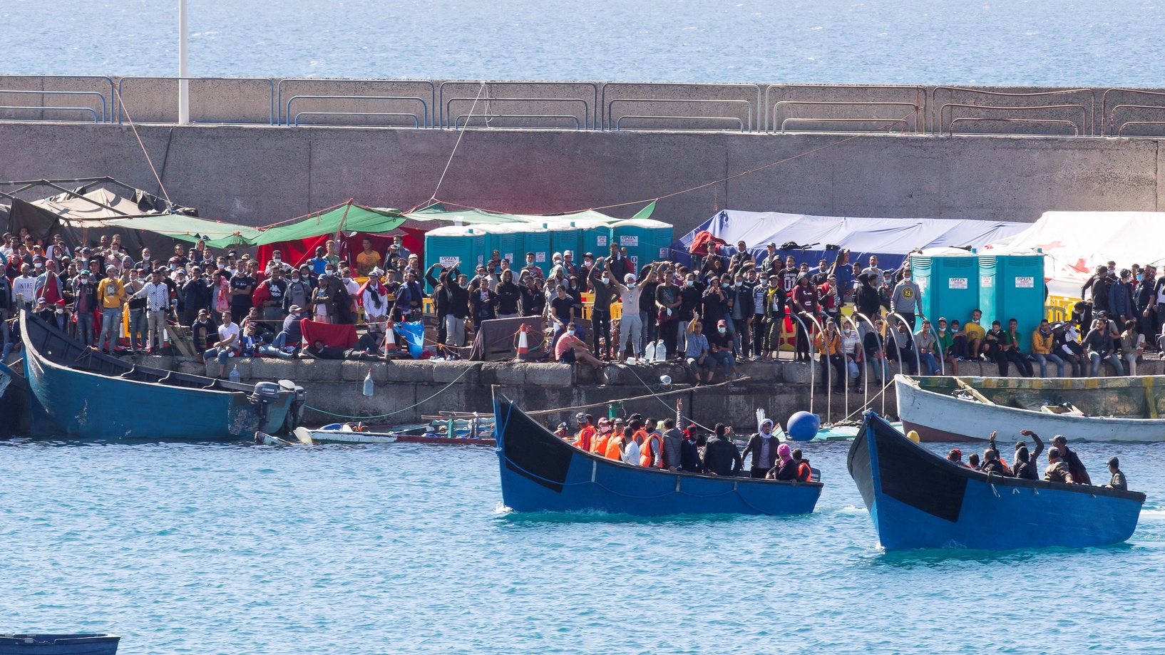 epa08825438 Two boats with migrants are welcomed by other migrants upon their arrival at Arguineguin port, Gran Canaria island, southwestern Spain, 17 November 2020. Spanish authorities rescued 206 migrants on 17 November and 346 migrants a day earlier off Canary Islands. In total, Spain has so far rescued some 17,000 migrants in 2020.  EPA/QUIQUE CURBELO