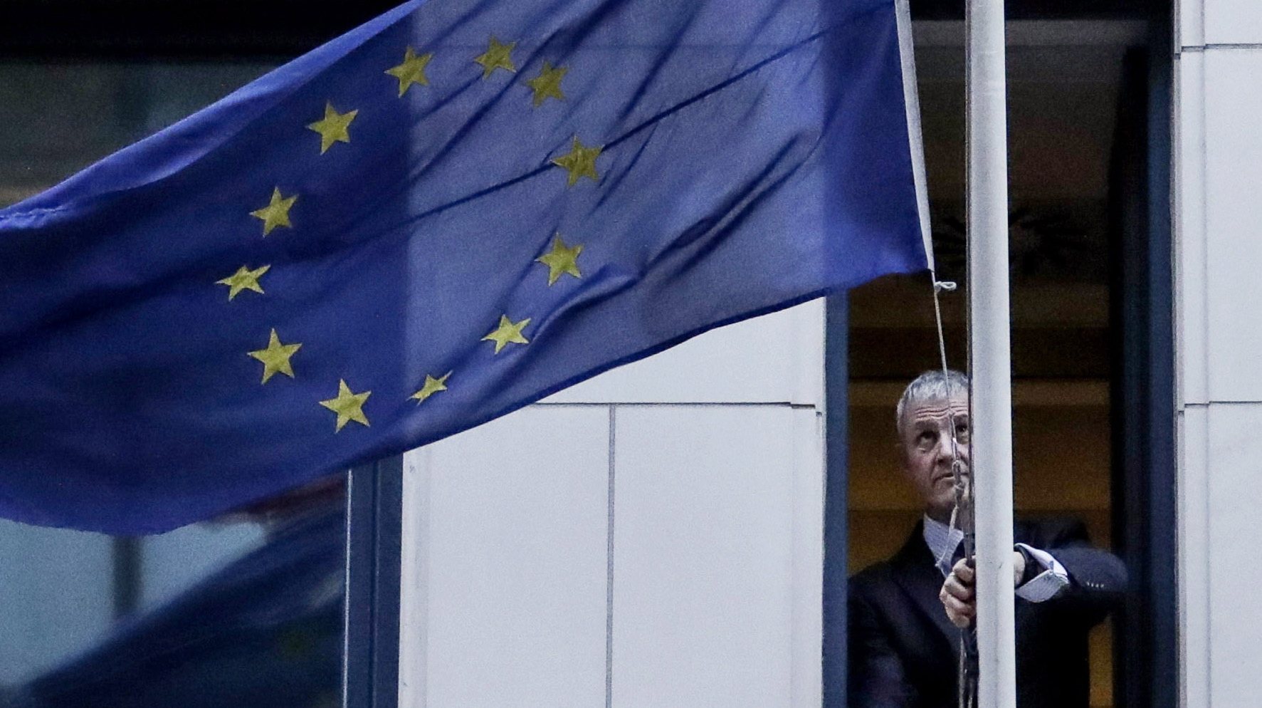 epaselect epa08182520 A man removes the European Union flag from the UK representation to the EU in Brussels, Belgium, 31 January 2020. Britain officially exits the EU on 31 January 2020, beginning an eleven month transition period.  EPA/OLIVIER HOSLET / POOL