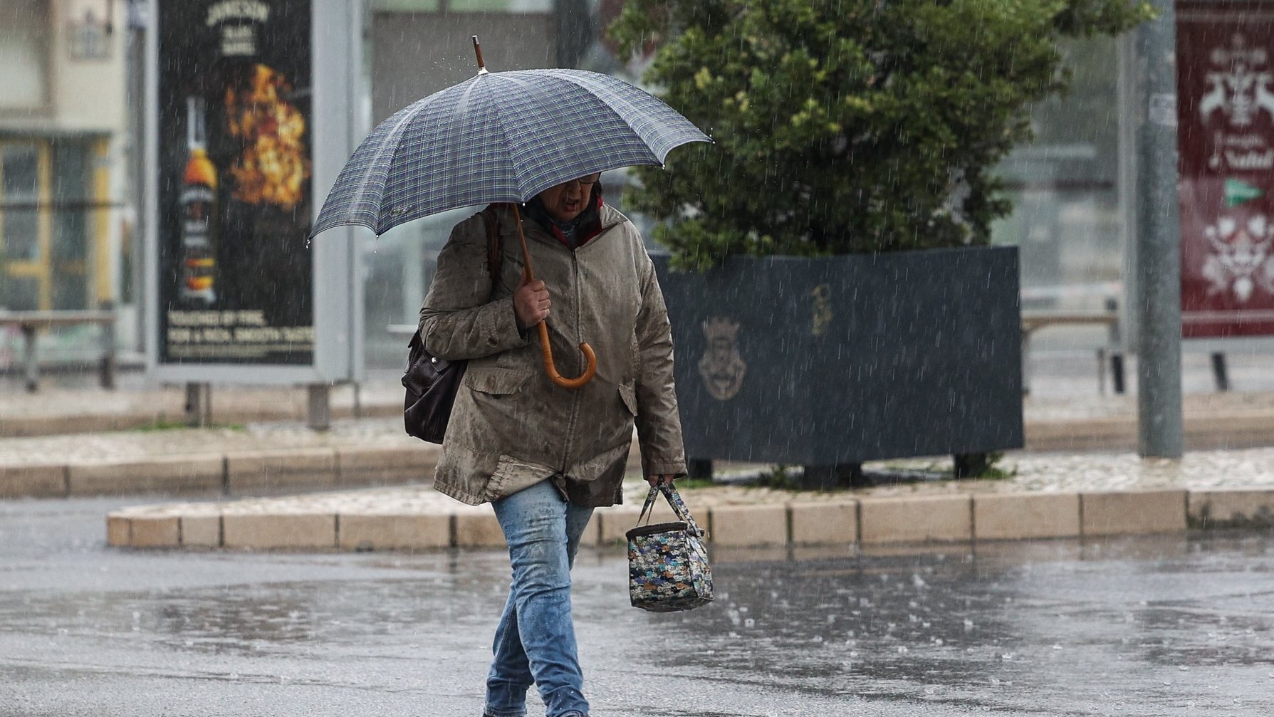 Traseunte passa com chapéu de chuva na zona de Algés em Oeiras num dia de temporal, 14 de dezembro de 2022. TIAGO PETINGA/LUSA