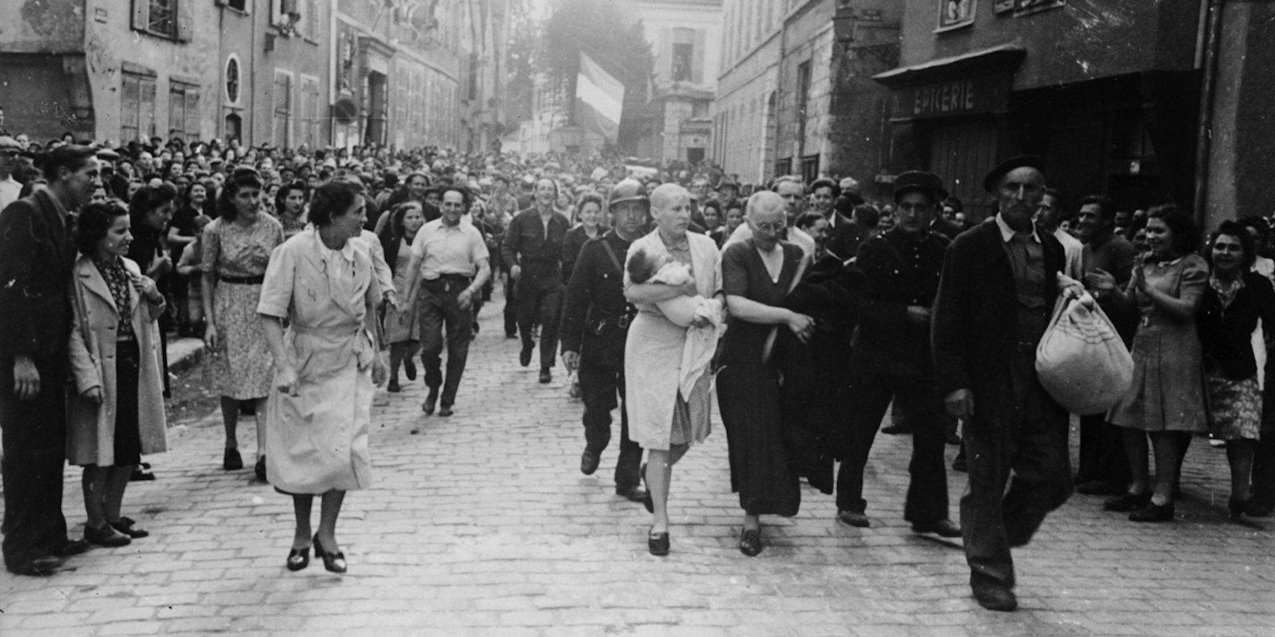 A woman, with her baby whose father is German, and her mother are jeered and humiliated by crowds in Chartres after having their heads shaved as punishment for collaborating with the German troops. (Photo by Robert Capa/Getty Images)