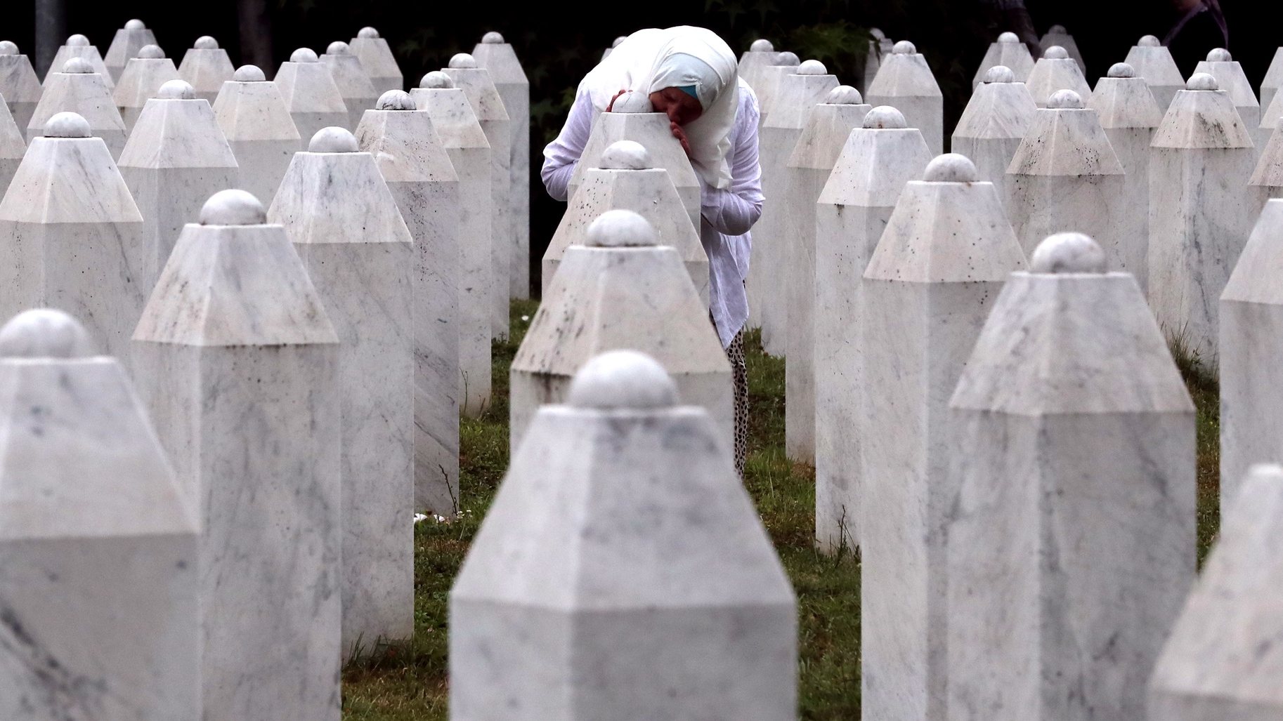 epaselect epa09336592 A Bosnian Muslim woman mourns while touching a gravestone during a funeral ceremony for nineteen newly-identified Bosnian Muslim victims, at the Potocari Memorial Center and Cemetery, in Srebrenica, Bosnia and Herzegovina, 11 July 2021. The burial was part of a memorial ceremony to mark the 26th anniversary of the Srebrenica genocide, considered the worst atrocity of Bosnia&#039;s 1992-95 war. More than 8,000 Muslim men and boys were executed in the 1995 killing spree after Bosnian Serb forces overran the town.  EPA/FEHIM DEMIR