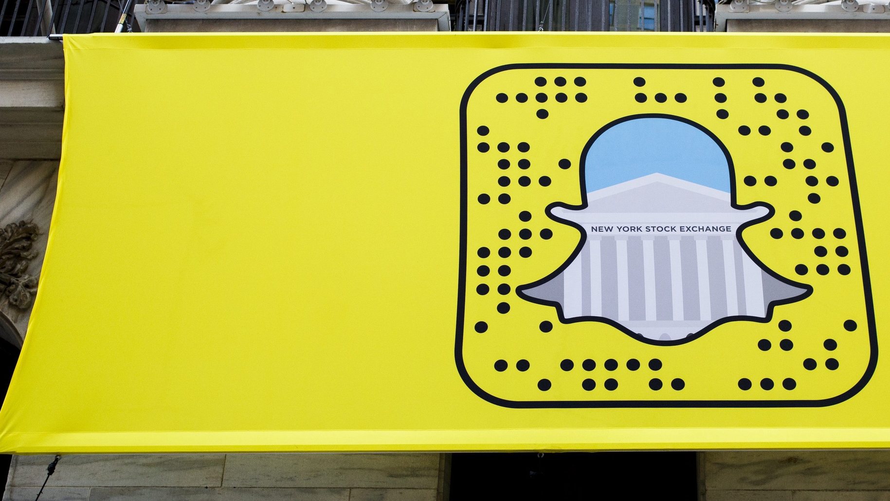 epa05635065 A logo for Snapchat hangs on the front of the New York Stock Exchange in New York, New York, USA, on 17 November 2016. Snap Inc., the parent company of Snapchat, has filed for an initial public offering which could come in March of 2017 and be valued at 20 - 25 billion US dollars (USD).  EPA/JUSTIN LANE