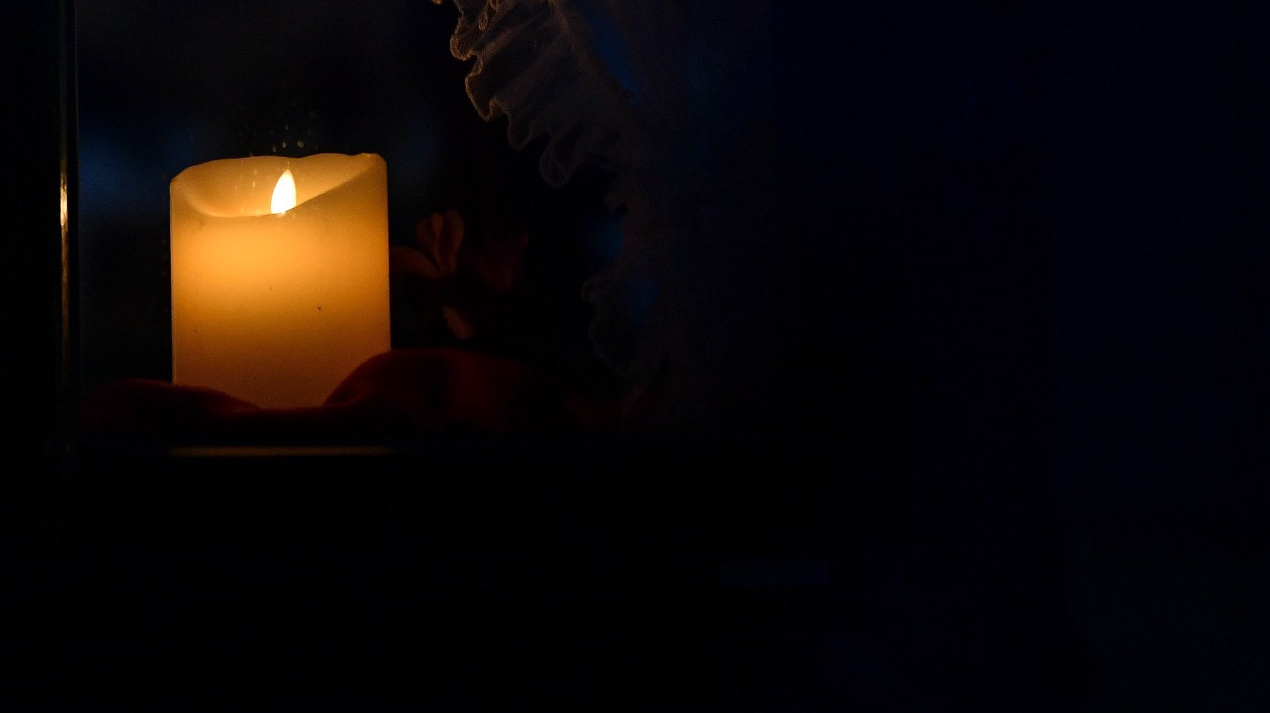 epa08958377 A candle is seen in a window at dawn in Garmisch-Partenkirchen, Germany, 22 January 2021. German President Steinmeier initiated the nationwide &#039;Lichtfenster&#039; (light window) campaign in memory of the victims of the COVID-19 coronavirus pandemic, encouraging citizens to show their mourning and solidarity by lighting a candle in their window or near their house.  EPA/PHILIPP GUELLAND