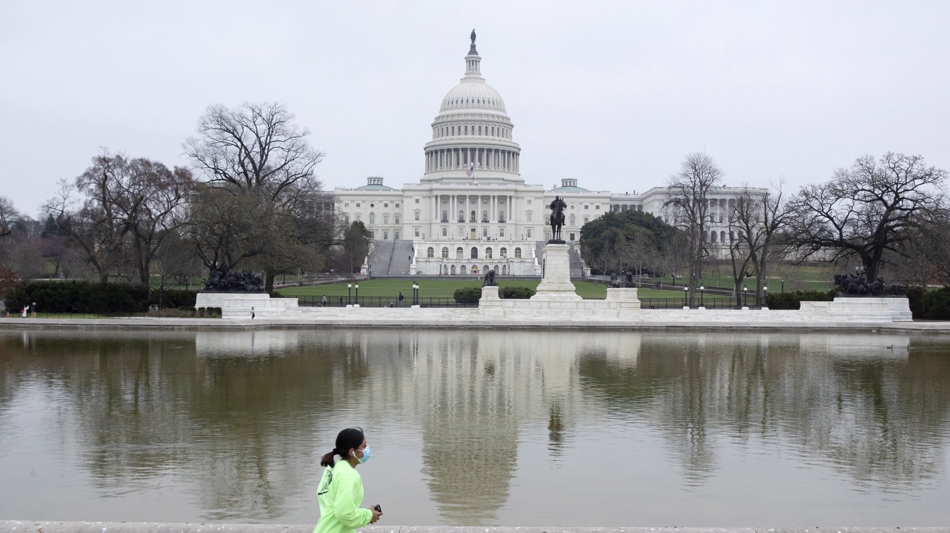 epa09097143 A jogger runs by the Capitol Reflecting Pool on Capitol Hill in Washington, DC, USA, 25 March 2021. The Capitol Reflecting Pool, just west of the US Capitol Building, became available for the public to visit this week for the first time since the 06 January mob riot attack on the Capitol. An inner perimeter security fence around the Capitol remains in place.  EPA/MICHAEL REYNOLDS