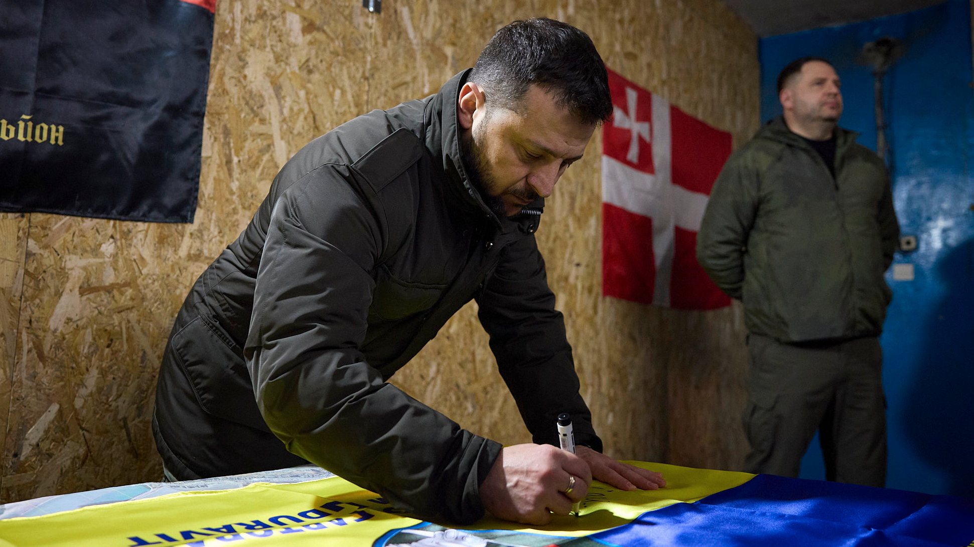epa11166132 A handout picture made available by the Presidential Press Service shows President of Ukraine Volodymyr Zelensky signing a flag during his visit to the battalion command post of the 14th separate mechanized brigade named after Prince Roman the Great, near a frontline in the Kupyansk area, Ukraine, 19 February 2024 amid the Russian invasion. Russian troops entered Ukrainian territory on 24 February 2022, starting a conflict that has provoked destruction and a humanitarian crisis.  EPA/PRESIDENTIAL PRESS SERVICE HANDOUT HANDOUT 44296 HANDOUT EDITORIAL USE ONLY/NO SALES HANDOUT EDITORIAL USE ONLY/NO SALES