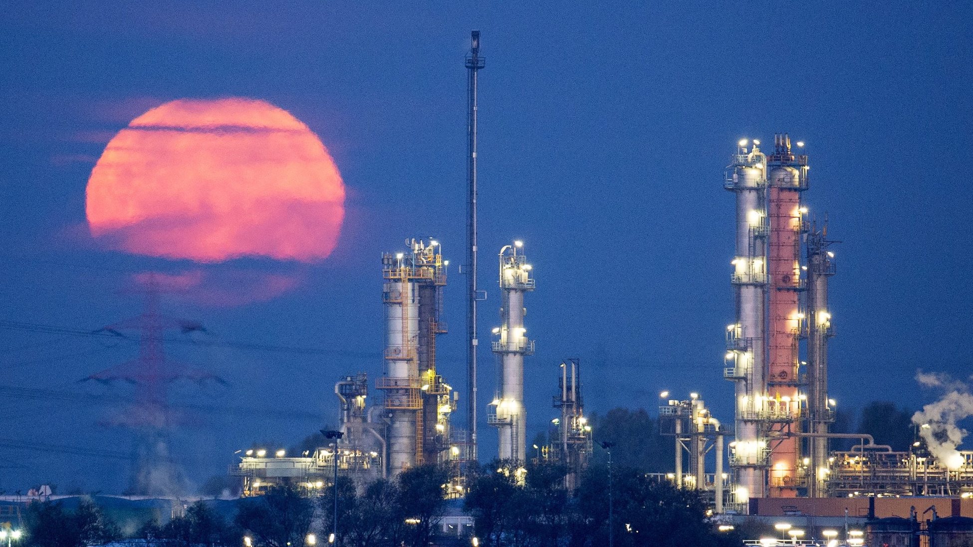 epa04998025 A full moon glows red behind an oil refinery in the port of Hamburg, Germany, 27 October 2015. Sunshine was forecast in the city, though mild autumnal temperatures were predicted.  EPA/DANIEL REINHARDT