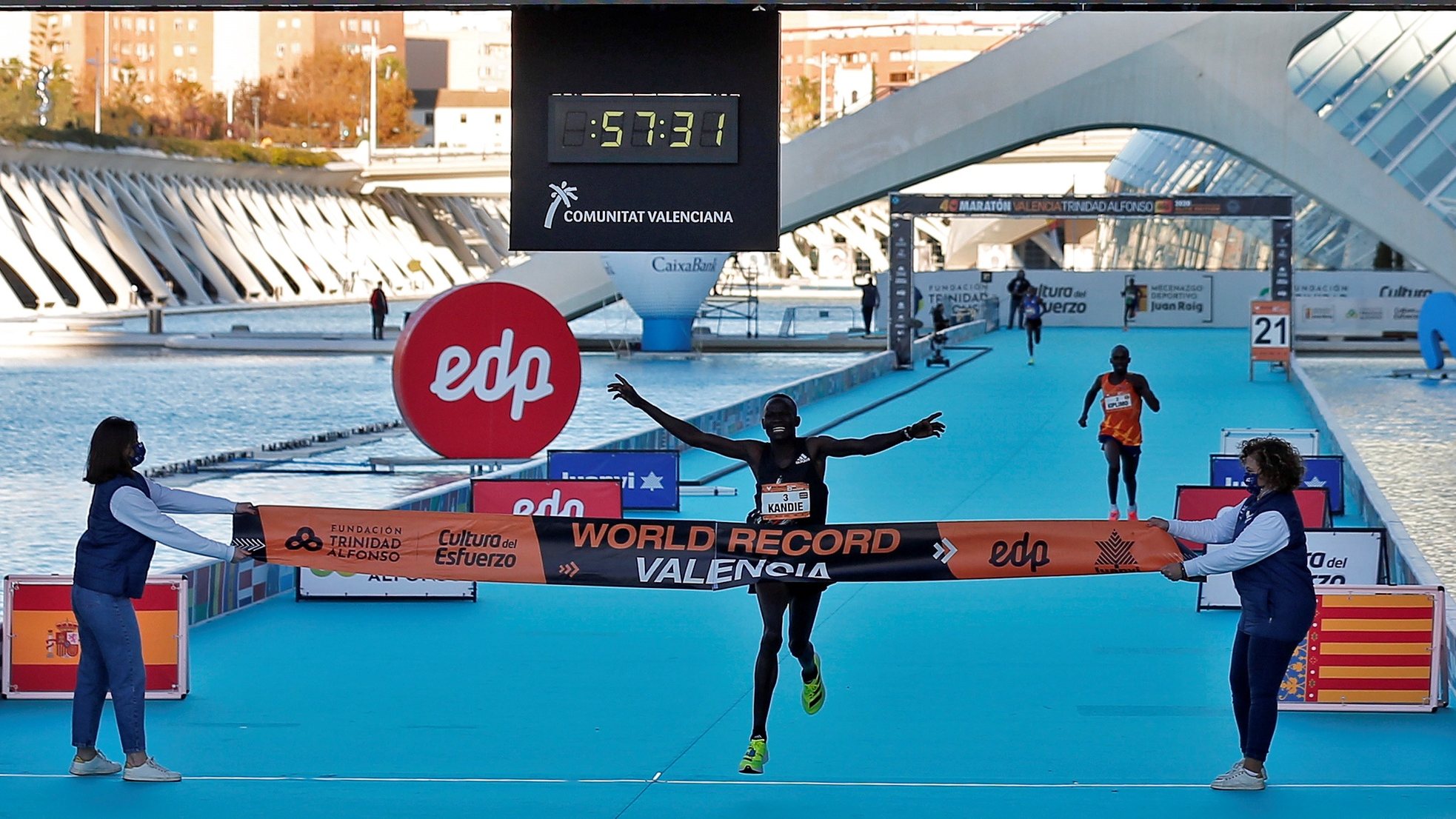 epa08865707 Kenyan athlete Kibiwott Kandie (C) crosses the finish line to break the World record and win the Valencia Half Marathon, in Valencia, Spain, 06 December 2020.  EPA/Manuel Bruque