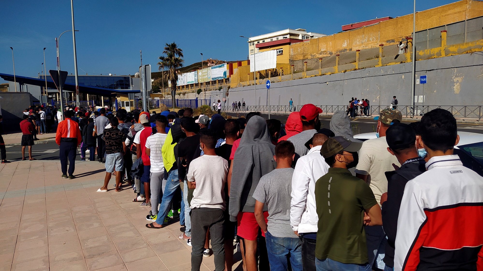 epa09242602 Moroccan migrants wait in a long queue in front of Asylum and Refuge Office at Tarajal border crossing in Ceuta, Spanish enclave in northern Africa, 02 June 2021. Most of the asylum seekers entered Ceuta on the last 17 and 18 May 2021, when some 10,000 people managed to reach Spain, mainly by sea, although some 8,000 of them came back to their country.  EPA/Reduan Dris