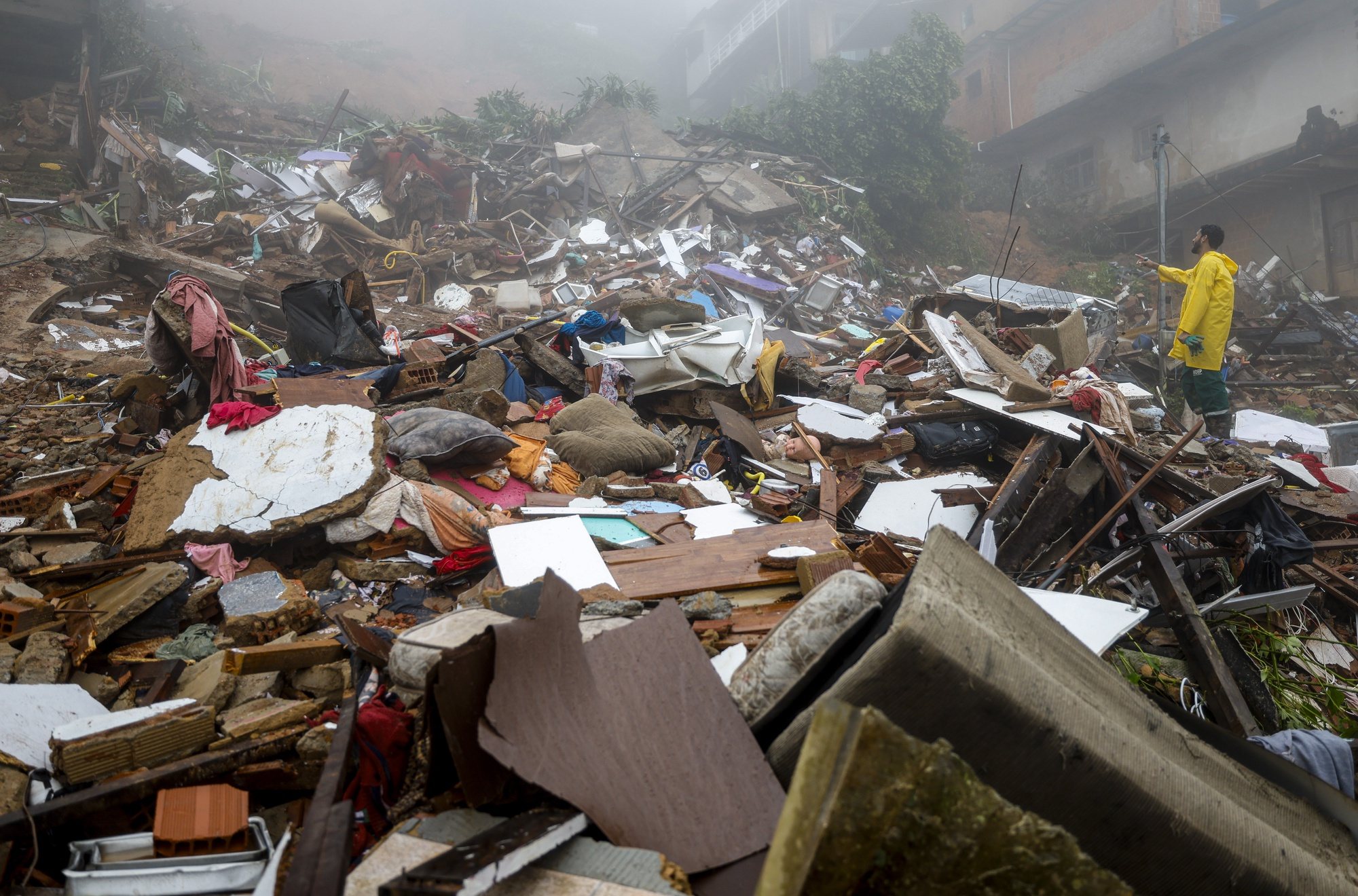 epa11239215 People search for victims or belongings in the debris caused by a landslide in Petropolis, Rio de Janiero state, Brazil, 23 March 2024. At least seven people have died in Rio de Janeiro upon landslides and deluges of water triggered by the heavy rains in the state.  EPA/Antonio Lacerda