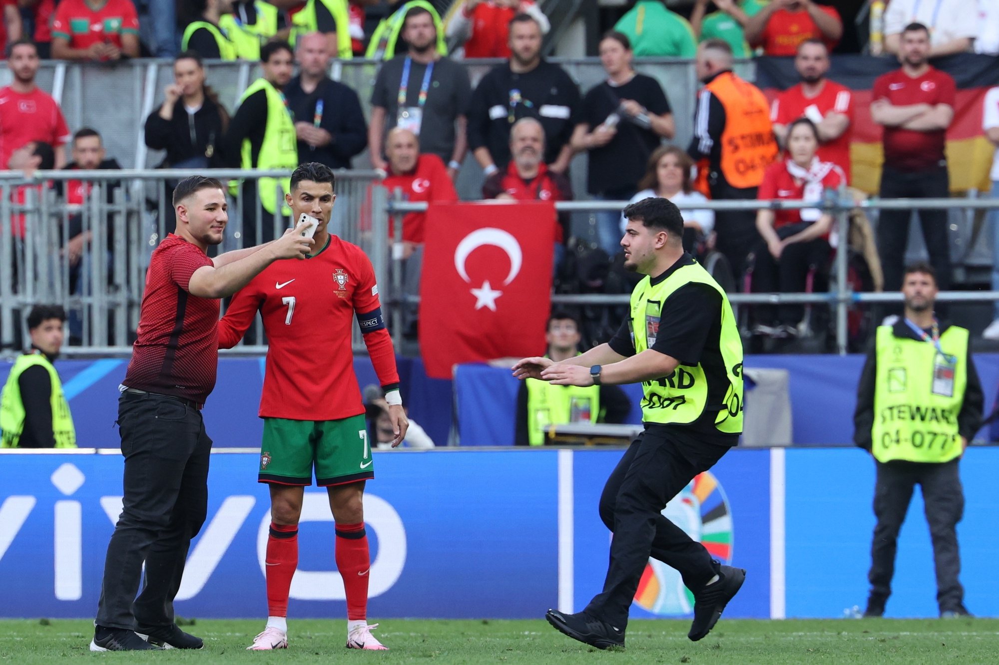 epa11431030 A pitch invader takes a selfie with Cristiano Ronaldo (2L) of Portugal during the UEFA EURO 2024 group F soccer match between Turkey and Portugal, in Dortmund, Germany, 22 June 2024.  EPA/GEORGI LICOVSKI