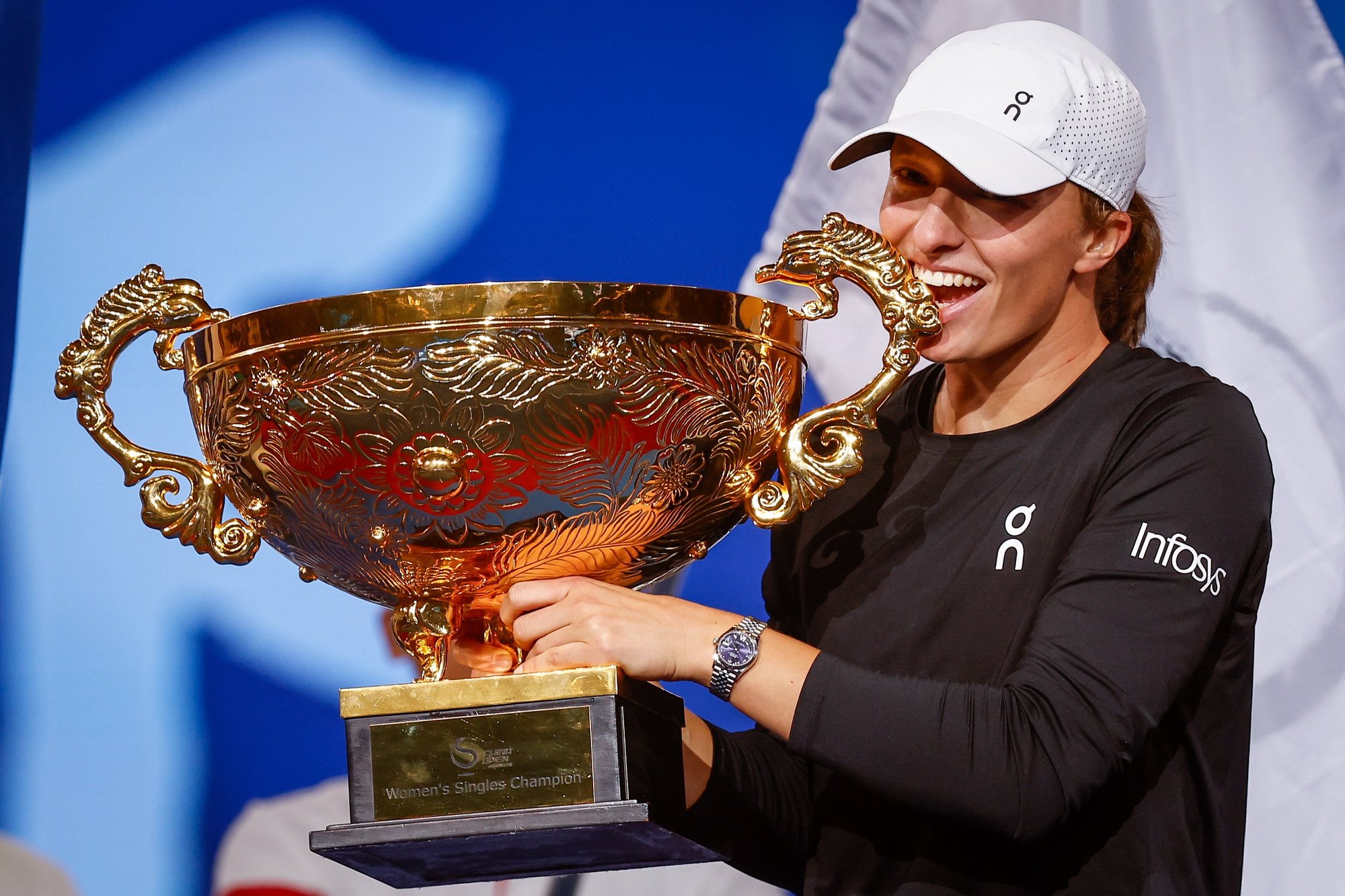 epa10907300 Iga Swiatek of Poland bites her trophy after winning the Women&#039;s Singles Final match against Liudmila Samsonova of Russia (not pictured) at the China Open tennis tournament in Beijing, China, 08 October 2023.  EPA/MARK R. CRISTINO