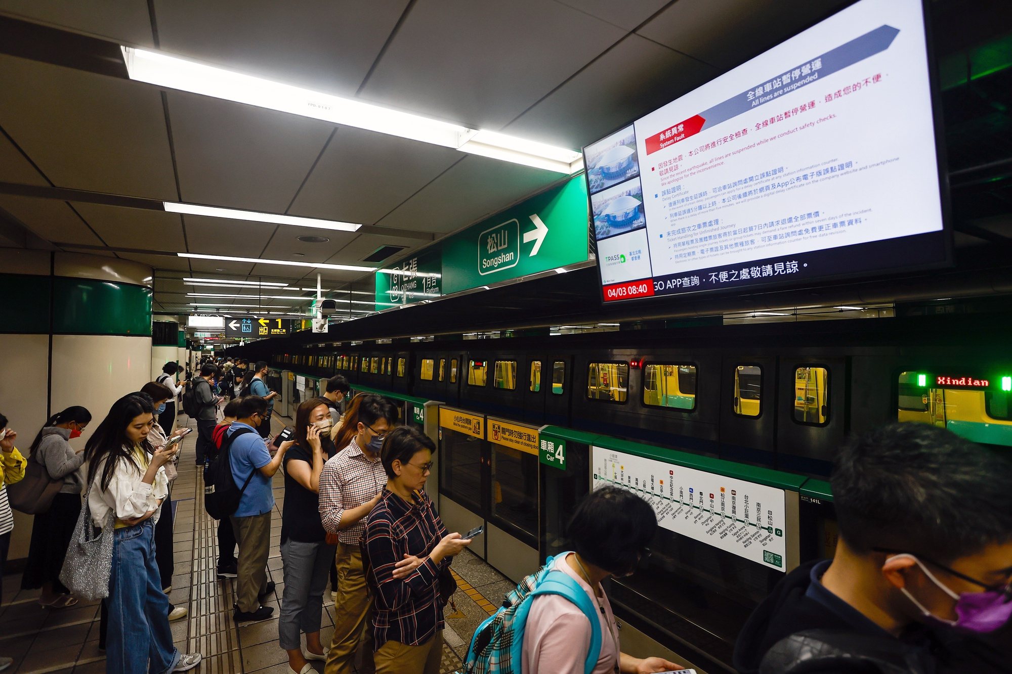 epa11256373 Passengers wait below a screen broadcasting a subway train suspension announcement following a magnitude 7.4 earthquake near Hualien, in a subway station in Taipei, Taiwan, 03 April 2024. A magnitude 7.4 earthquake struck Taiwan on the morning of 03 April with an epicentre 18 kilometres south of Hualien City at a depth of 34.8 km, according to the United States Geological Survey (USGS).  EPA/DANIEL CENG