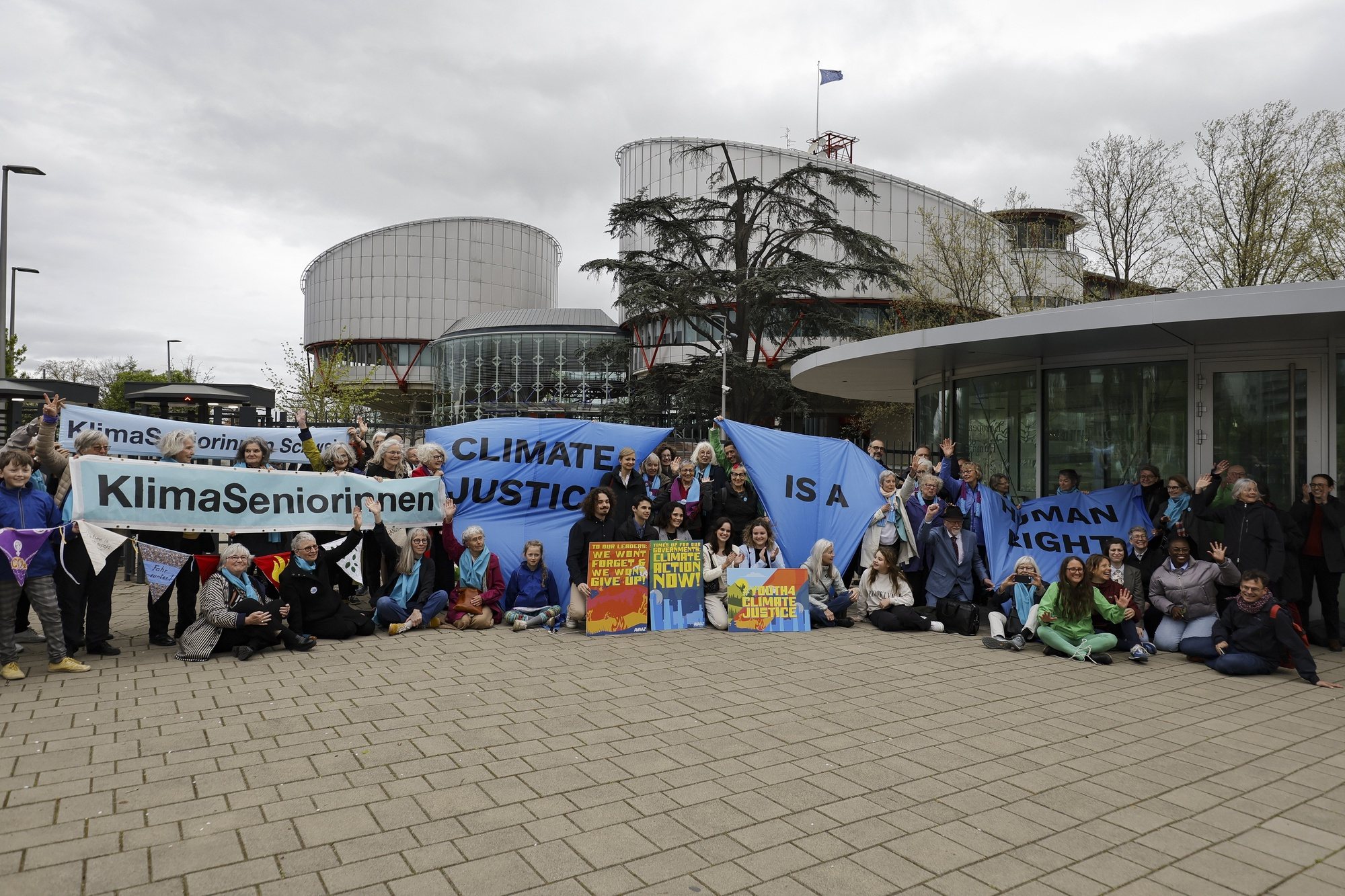 epa11266815 Activists pose with protest banners and placards in front of the European Court of Human Rights (ECHR), before the judgment in a case against different European countries accused of climate inaction, at the European Court of Human Rights in Strasbourg, France, 09 April 2024. The Strasbourg-based court was asked to rule in a trio of cases brought by a French mayor, six Portuguese young people, and more than 2,000 members of Switzerland&#039;s Senior Women for Climate Protection. Judges are to rule on complaints brought against Portugal, Switzerland, and France over carbon emissions. The ruling of the European Court of Human Rights could set a precedent for all its signatory members.  EPA/RONALD WITTEK