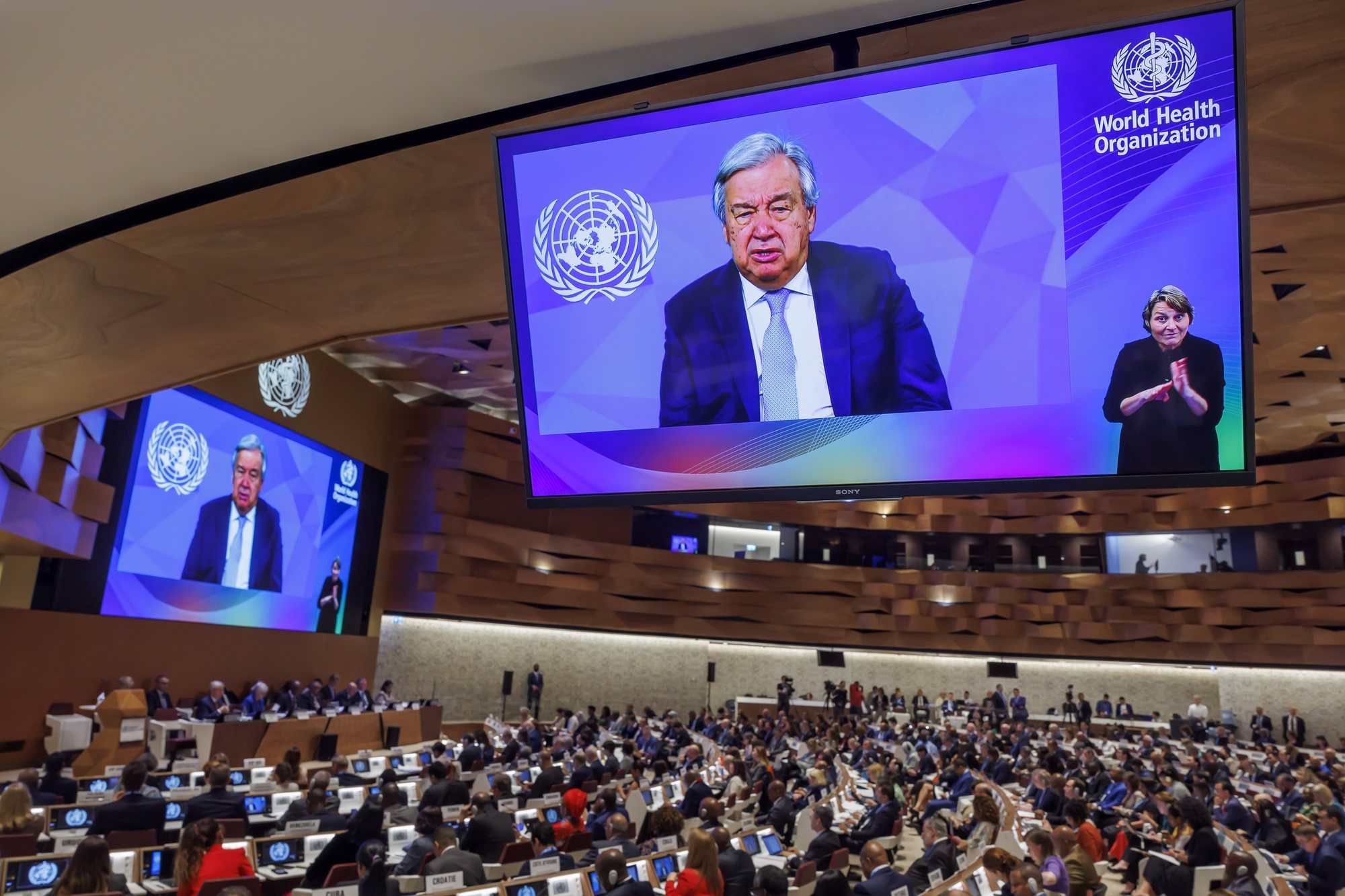 epa11373074 United Nations (UN) Secretary-General Antonio Guterres (on screens) delivers a remote statement, during the opening of the 77th World Health Assembly (WHA77) at the European headquarters of the United Nations in Geneva, Switzerland,  27 May 2024. This year&#039;s World Health Assembly is taking place from 27 May through 01 June 2024 and is &#039;focusing on the resolution on Social participation for universal health coverage, health and well-being and election advocacy&#039;, the organization announces on their website.  EPA/SALVATORE DI NOLFI