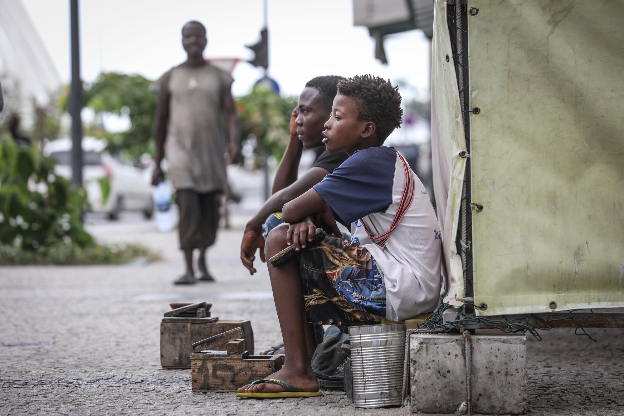 Jovens engraxadores aguardam por clientes numa rua em Luanda, Angola, 03 de junho de 2024. Engraxar sapatos ou catar lixo em contentores são atividades onde estão mergulhadas centenas de “candengues” (crianças) em idade escolar que deambulam em pequenos grupos pelas ruas da capital angolana. (ACOMPANHA TEXTO DA LUSA DO DIA 10 DE JUNHO DE 2024). AMPE ROGÉRIO/LUSA