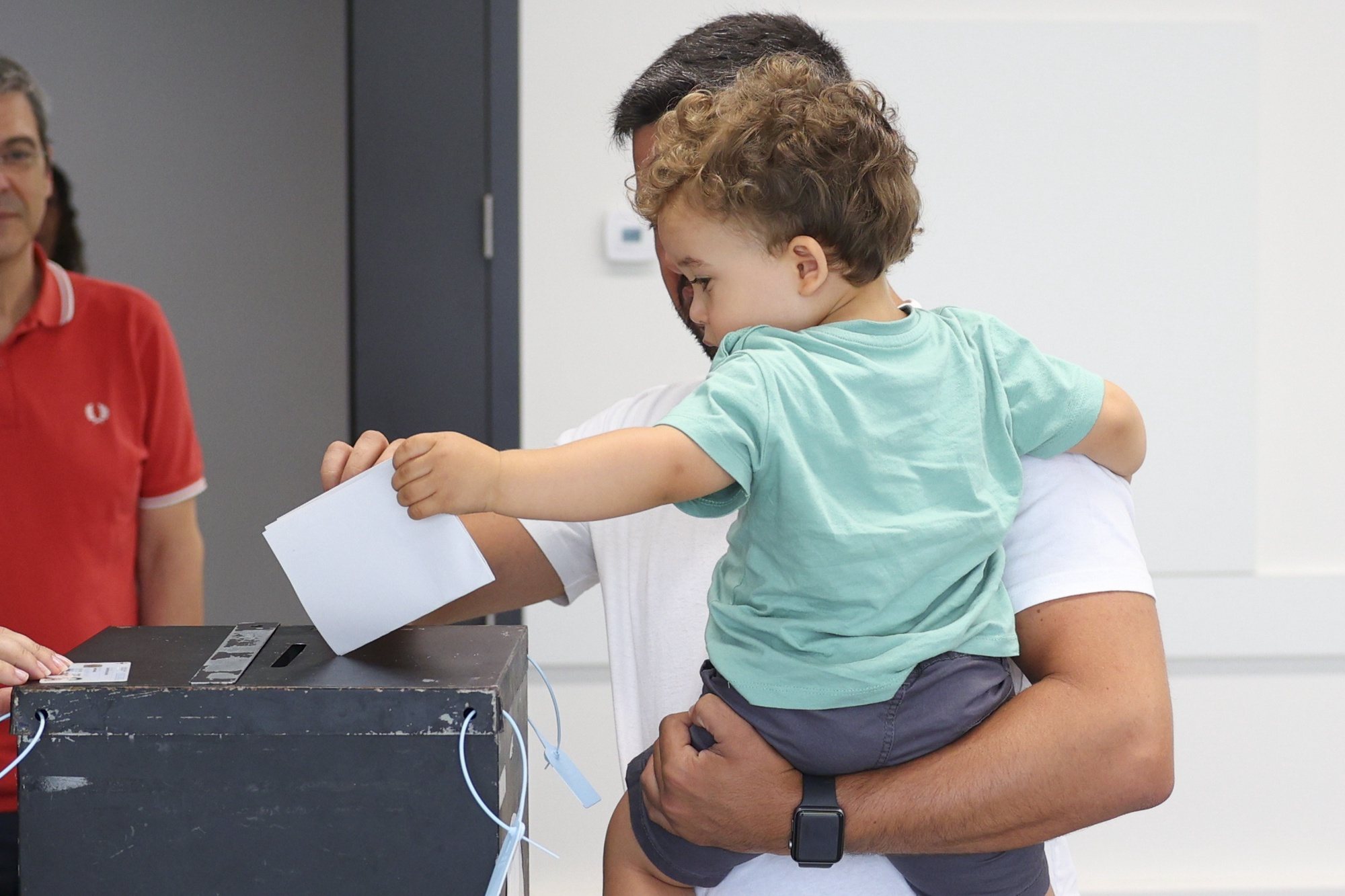 epa11399599 A chid helps his father to cast his ballot for the European Elections at a polling station in Lisbon, Portugal, 09 June 2024. More than 10.8 million registered voters in Portugal and abroad go to the polls on 09 June to choose 21 of the European Parliament&#039;s 720 members.  EPA/ANTONIO COTRIM