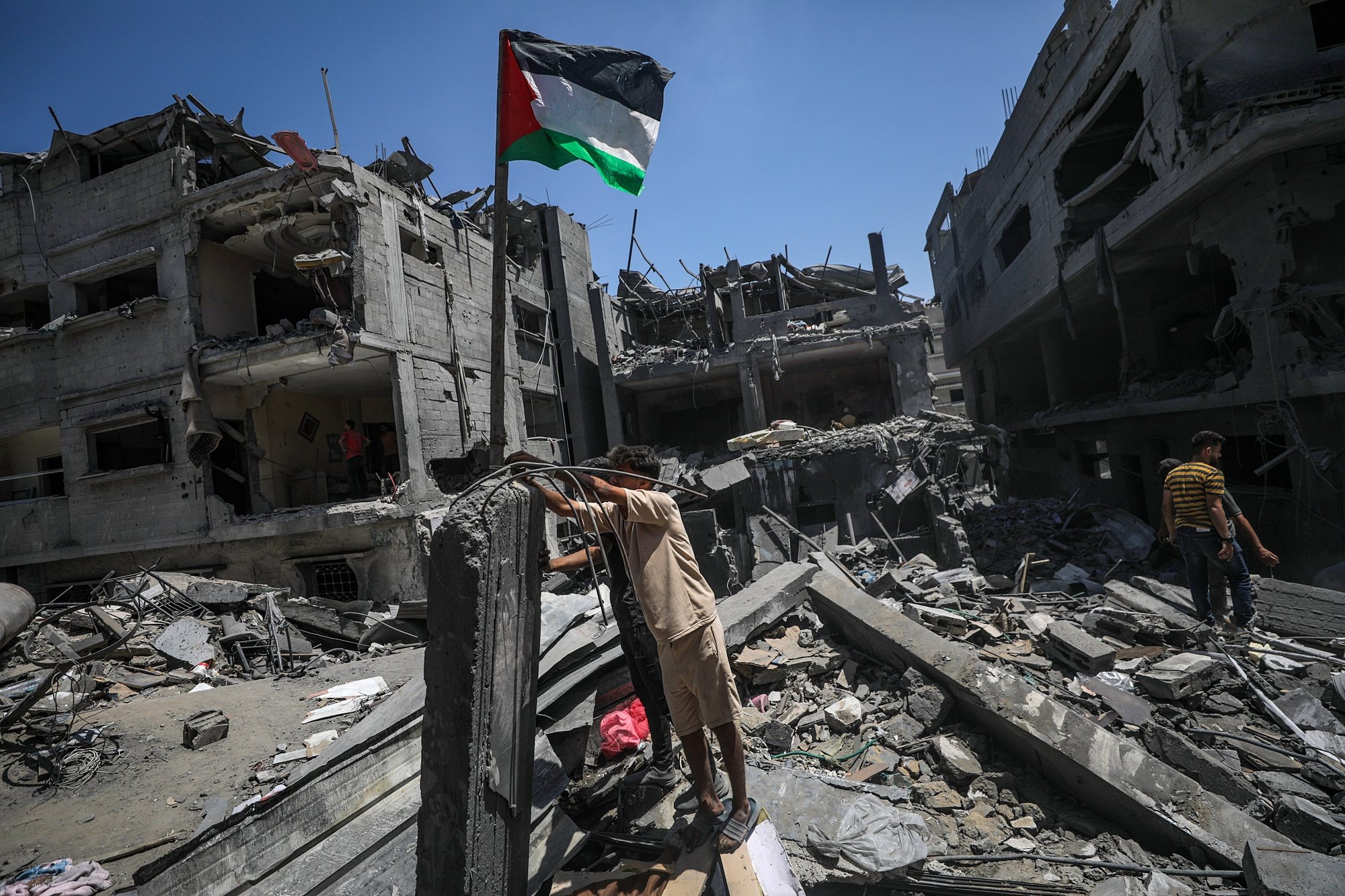 epaselect epa11419600 Palestinians raise a Palestinian flag next to their destroyed house following an Israeli air strike at al-Bureij refugee camp, southern Gaza Strip, 18 June 2024. More than 37,000 Palestinians and over 1,400 Israelis have been killed, according to the Palestinian Health Ministry and the Israel Defense Forces (IDF), since Hamas militants launched an attack against Israel from the Gaza Strip on 07 October 2023, and the Israeli operations in Gaza and the West Bank which followed it.  EPA/MOHAMMED SABER