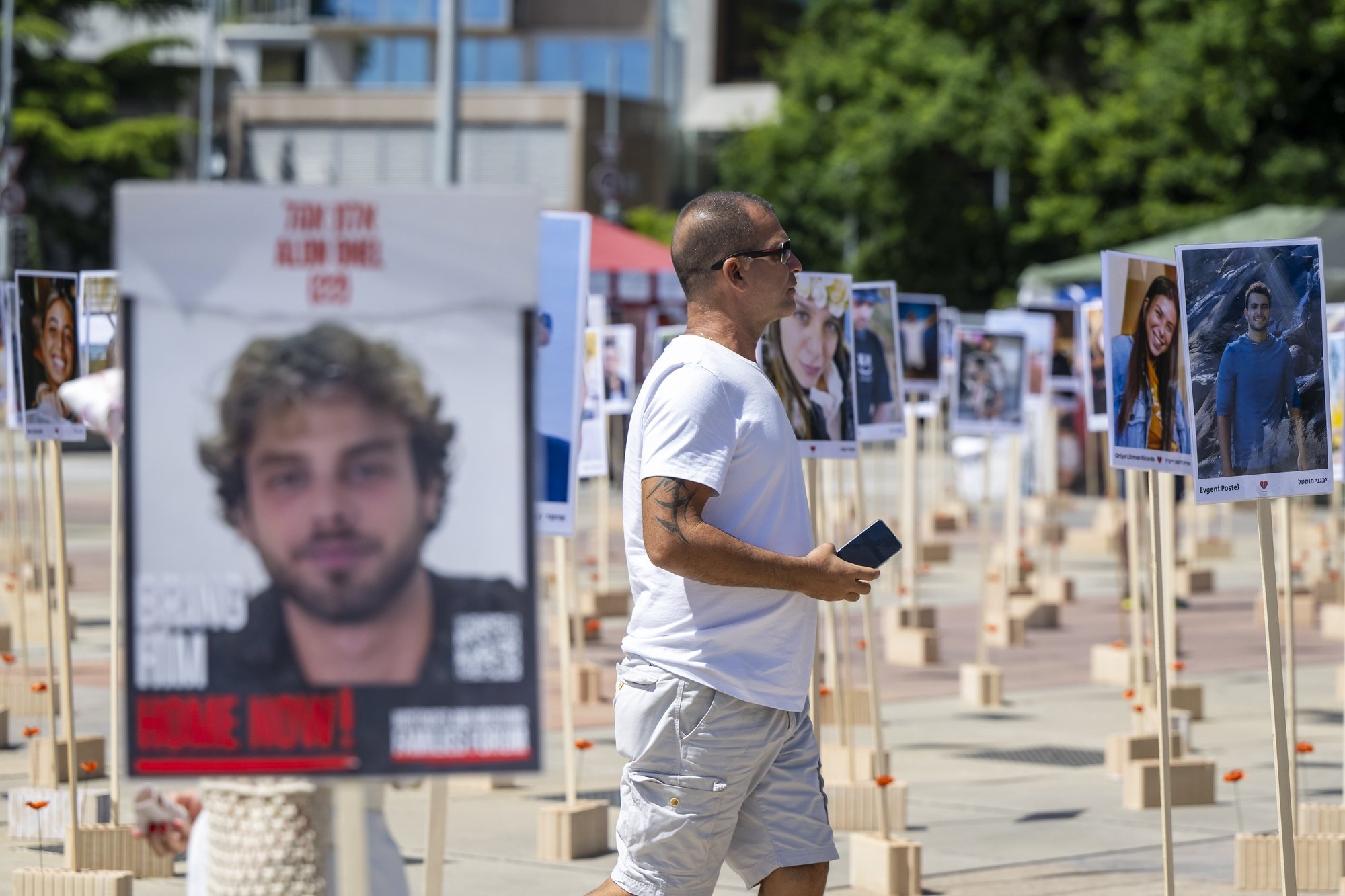 epa11422549 A person looks at portraits of Israeli hostages kidnapped by Hamas militants during the October 7 attacks that are installed in front of the United Nations European headquarters in Geneva, Switzerland, 19 June 2024, during the 56th session of the Human Rights Council.  EPA/MARTIAL TREZZINI